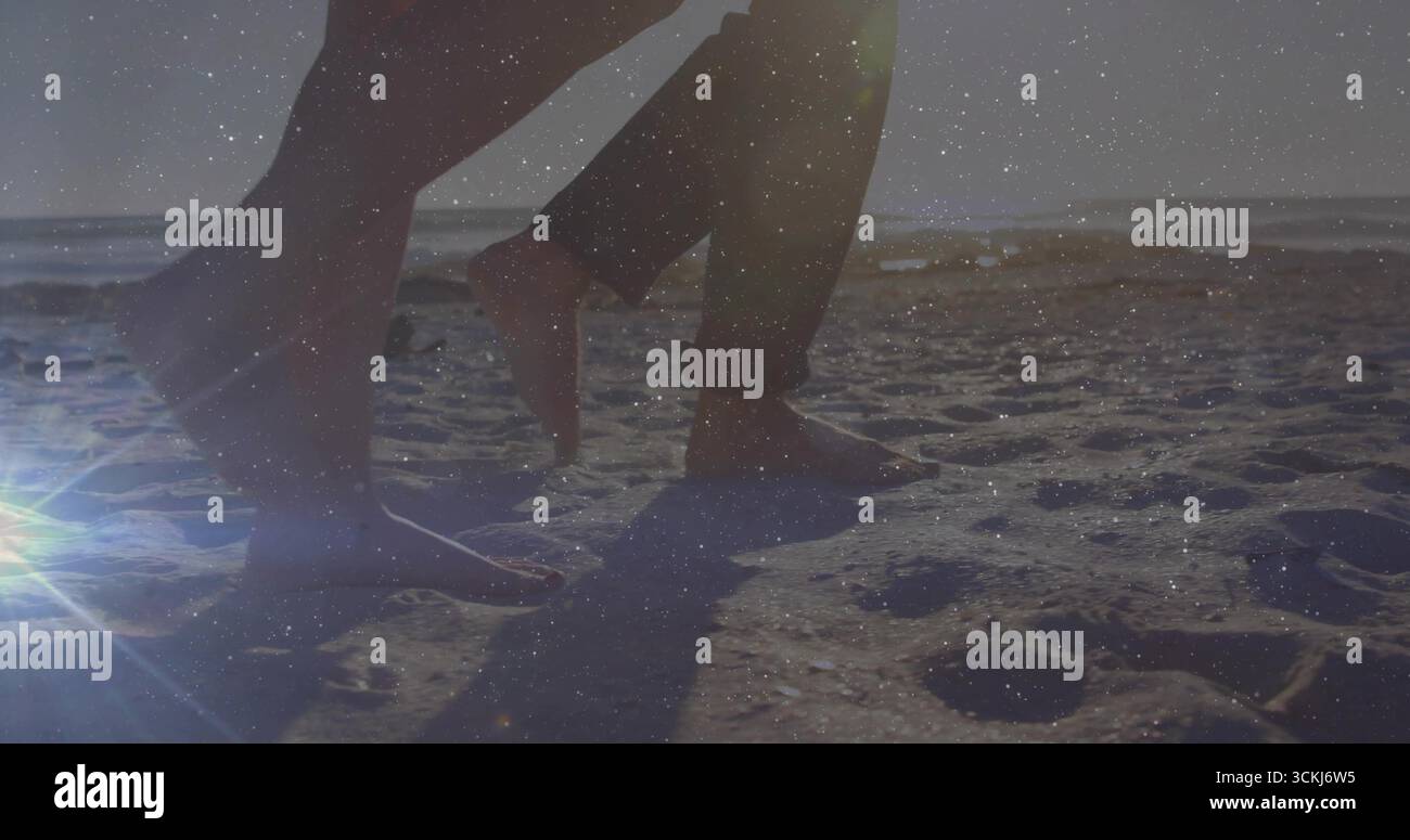 Parte inferiore delle gambe e dei piedi lungo il litorale, con pantaloni arrotolati, scarpe, scarpe, bagliore dell'obiettivo Foto Stock