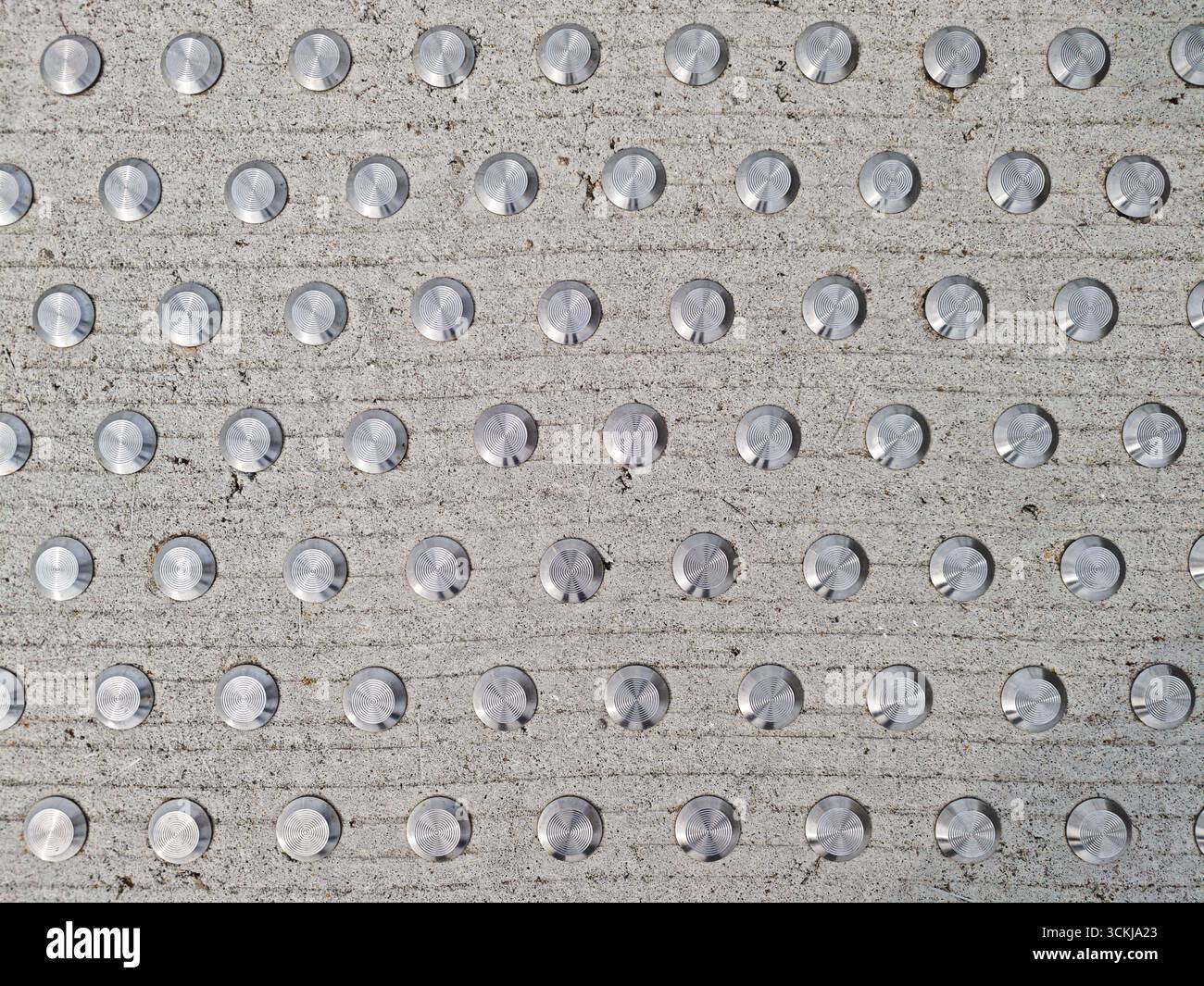 Primo piano di pavimentazione tattile con perni metallici su superfici in calcestruzzo per una guida cieca . Foto di alta qualità Foto Stock