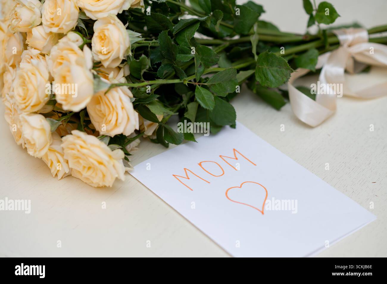 Biglietto d'auguri per bambini fatto a mano per la festa della mamma con un bouquet di rose gialle fresche, che simboleggia l'amore, la famiglia e la celebrazione della maternità Foto Stock
