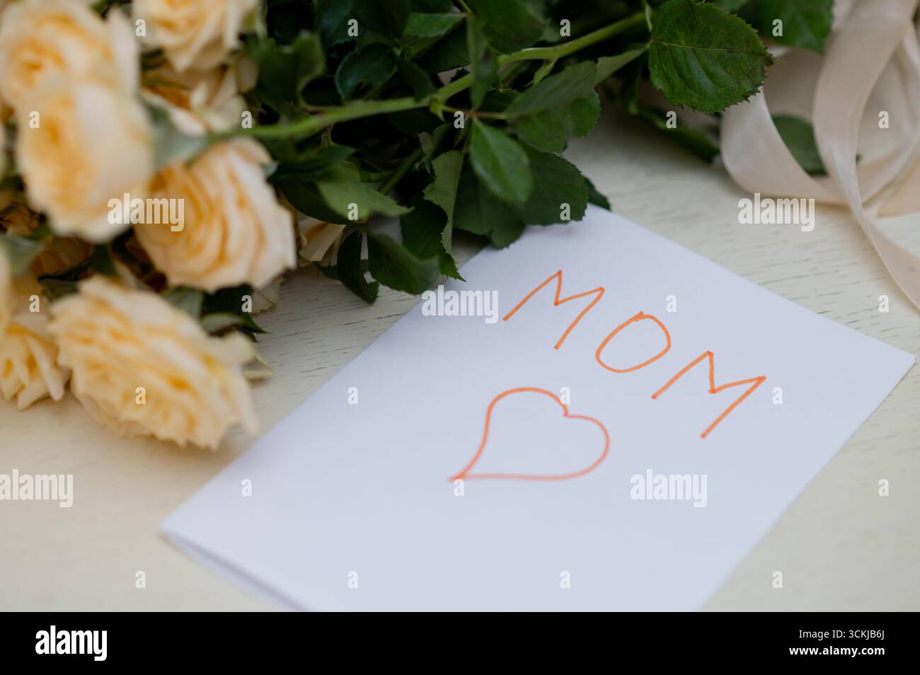 Biglietto d'auguri per bambini fatto a mano per la festa della mamma con un bouquet di rose gialle fresche, che simboleggia l'amore, la famiglia e la celebrazione della maternità Foto Stock