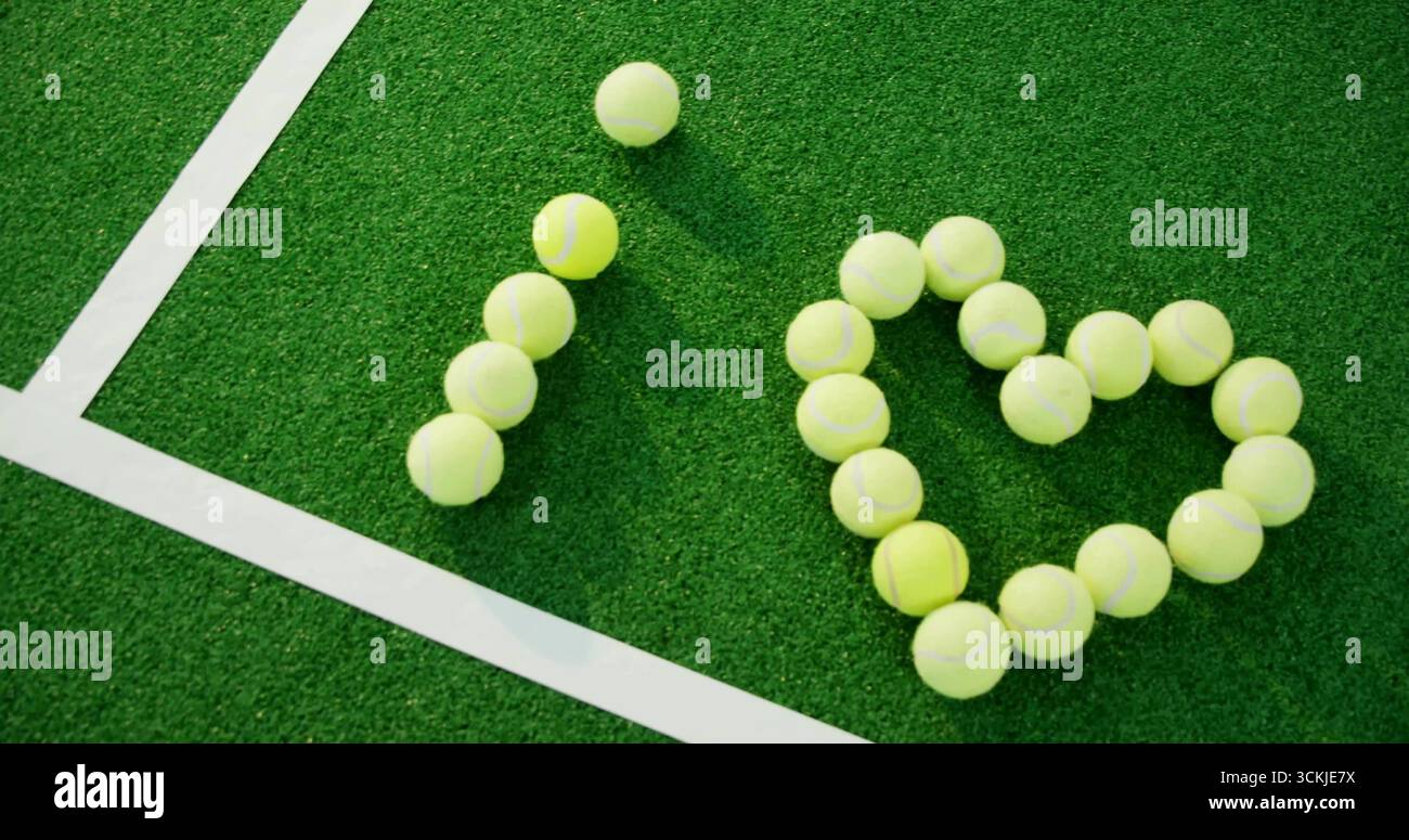 Mostra palle da tennis gialle che formano la forma del cuore sull'angolo del campo da tennis, con linee bianche Foto Stock