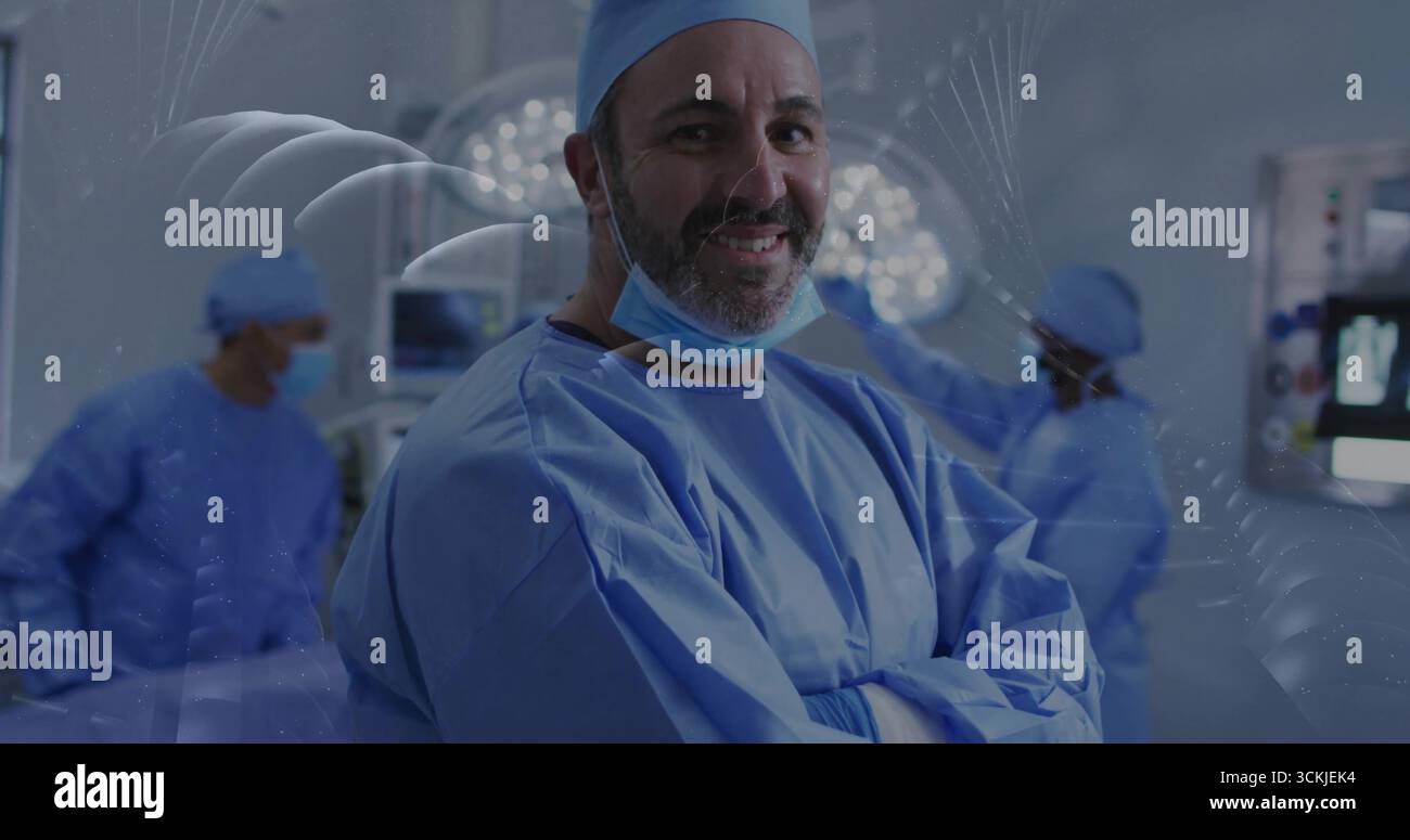 Chirurgo in posizione eretta in scrub blu, bracci pieghevoli in sala operatoria, con luci a soffitto e monitor Foto Stock