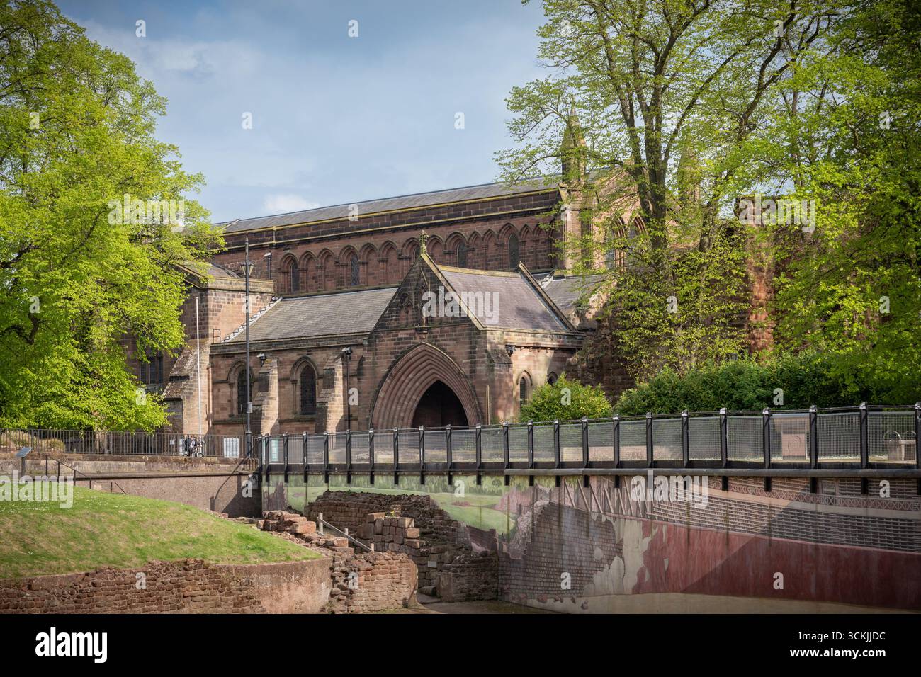 Vista della chiesa parrocchiale di San Giovanni Battista a Chester, Inghilterra, sotto un cielo azzurro, che mette in risalto l'architettura storica e la torre della chiesa. Foto Stock