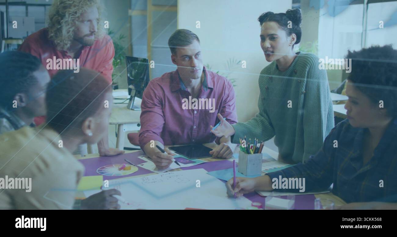 Discutere di sei colleghi che esaminano gli schizzi intorno al tavolo nello spazio di lavoro, con tablet e matite Foto Stock
