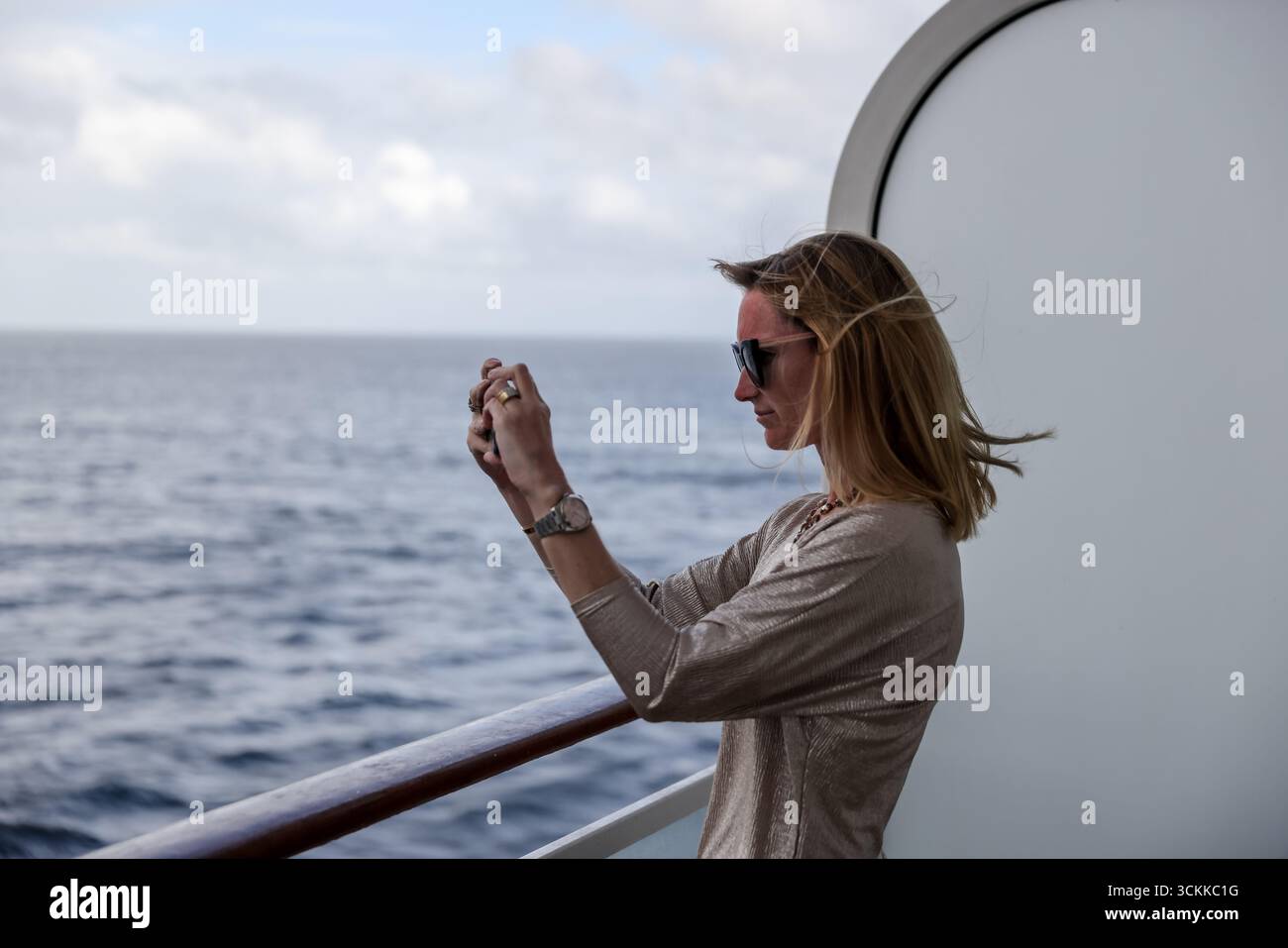 Cape Horn, Cile – 27 dicembre 2022: Woman scatta una foto dal patio di una cabina di una nave da crociera, nei tempeste mari del sud intorno a Cape Horn Foto Stock