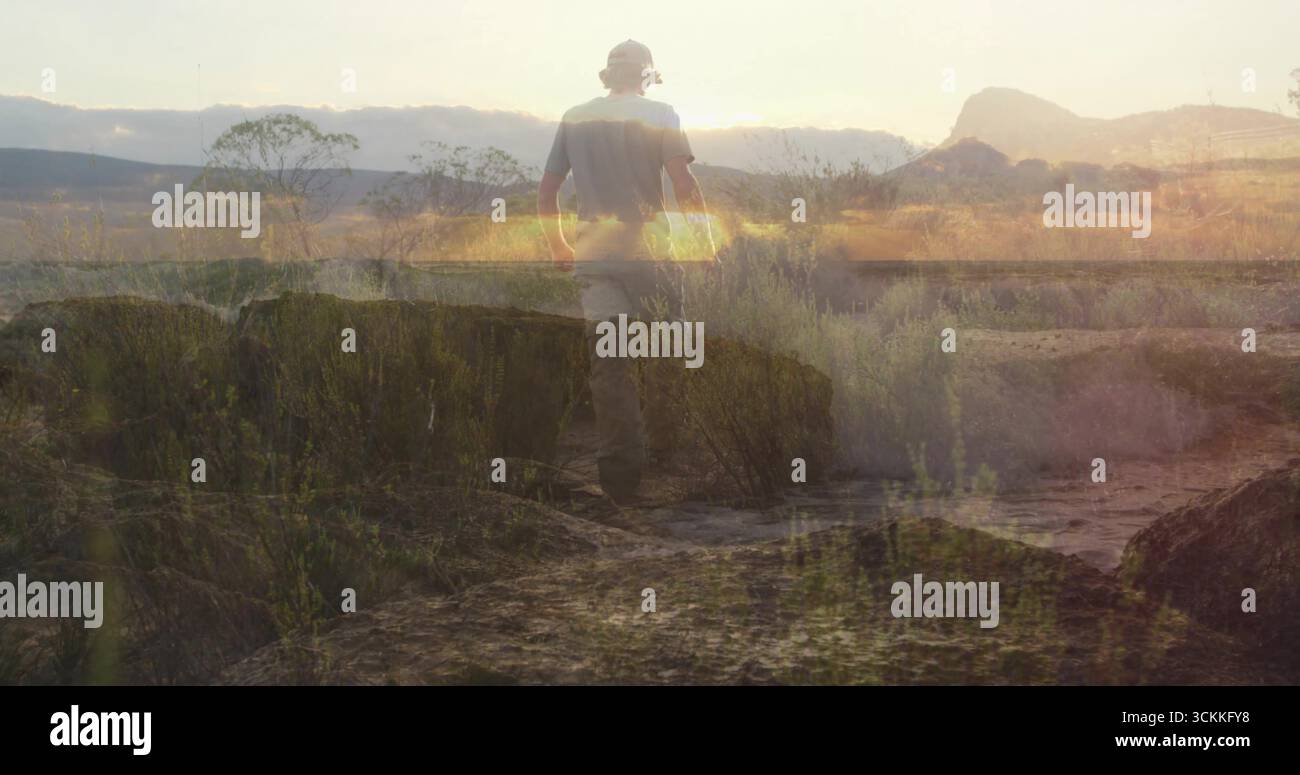 Escursionista che indossa un cappello da trekking a tegole larghe lungo il percorso del deserto al tramonto, con un bagliore dorato Foto Stock