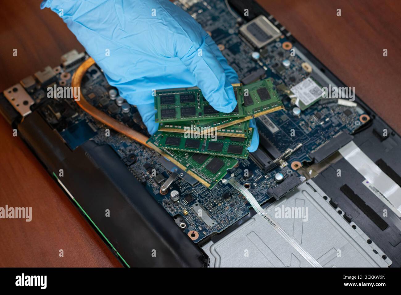 Un tecnico sta trattenendo la RAM per controllare e riparare la scheda madre del computer. Foto Stock