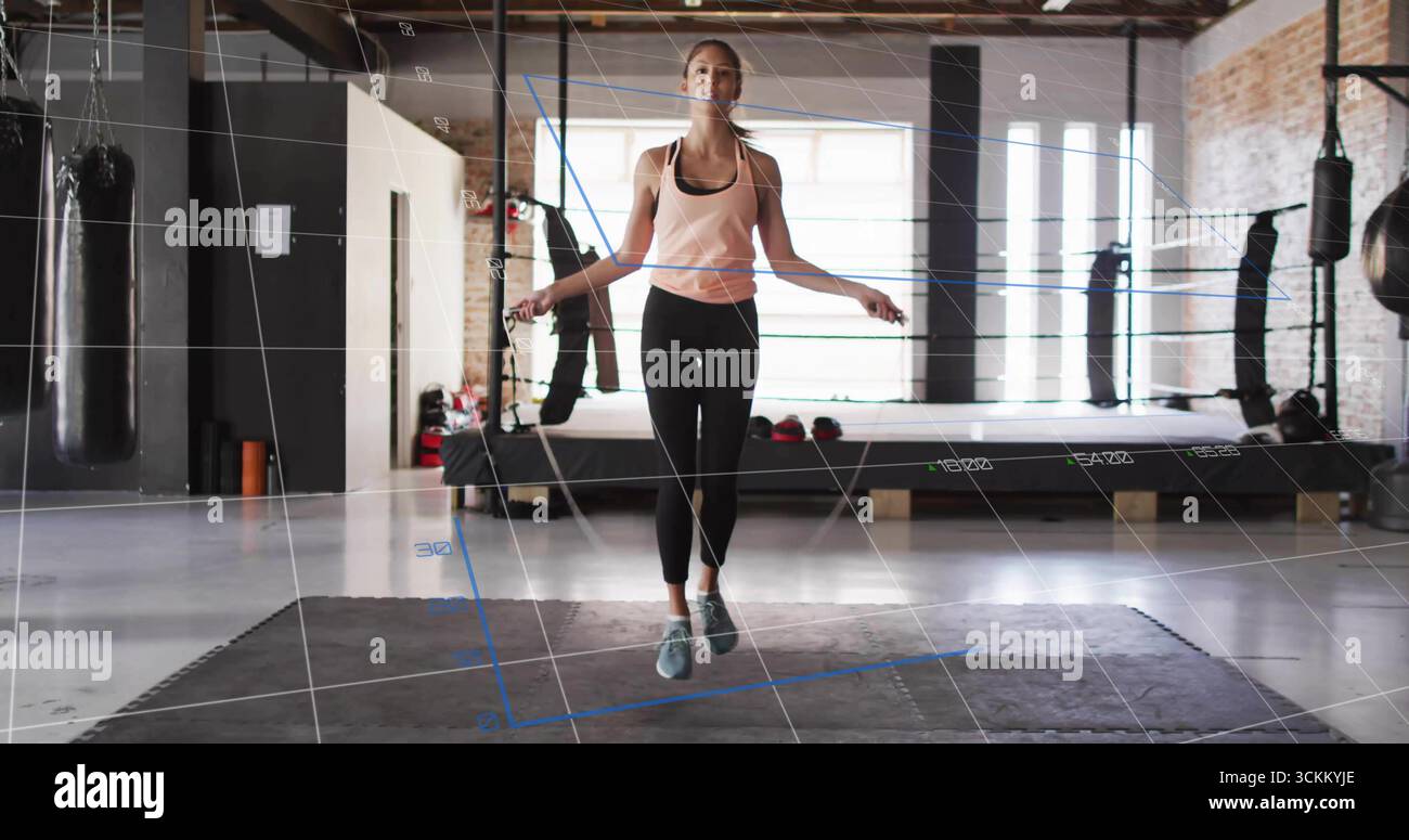 Atleta di salto che indossa una corda rosa con canotta per saltare nella palestra di boxe, con sacchetti di pugno e guanti Foto Stock Atleta di salto che indossa una corda rosa con canotta per saltare nella palestra di boxe, con sacchetti di pugno e guanti Foto Stock
