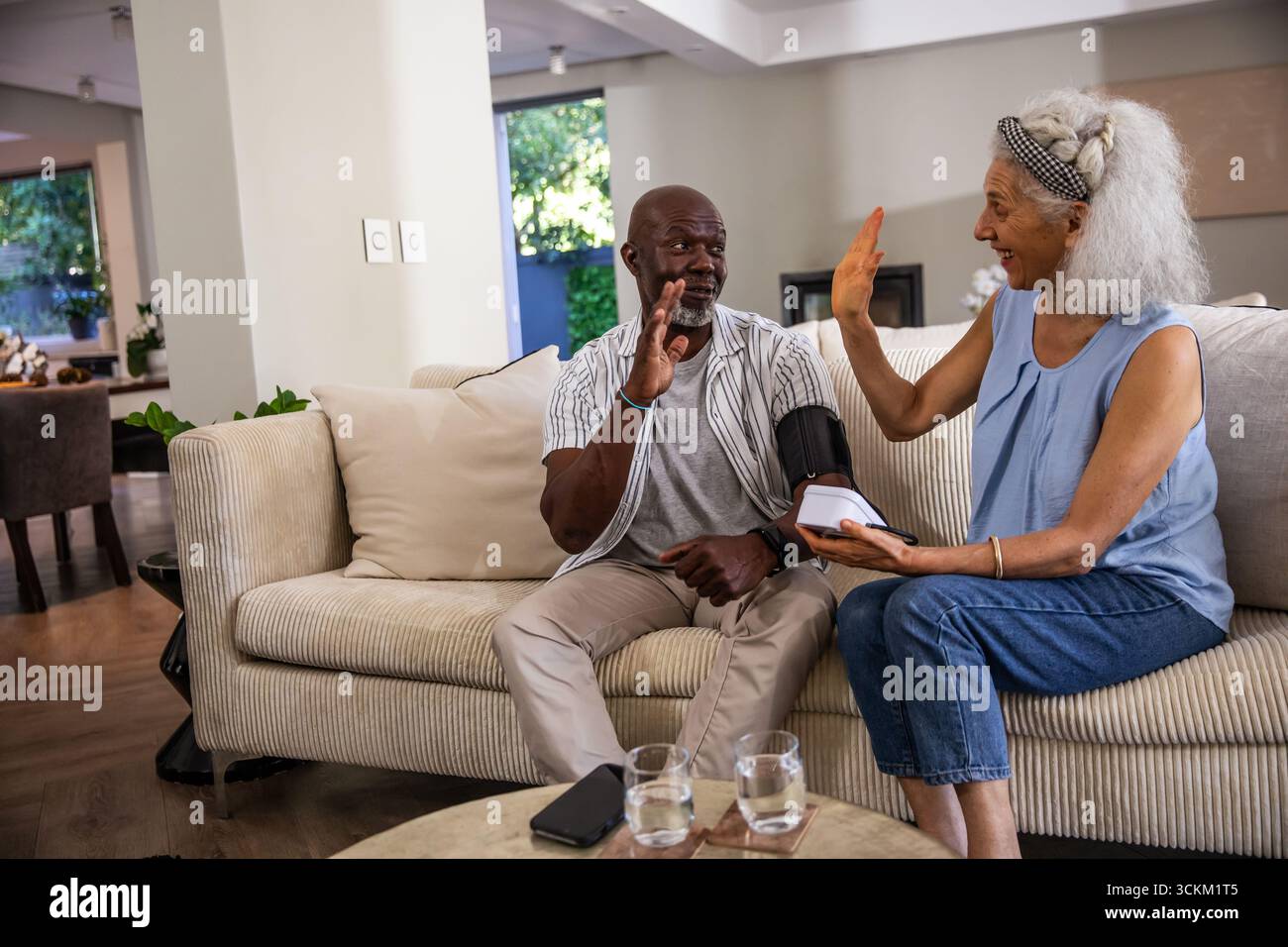 Diverse coppie anziane che rilevano la pressione sanguigna sul divano e che sono molto esigenti con il monitor Foto Stock