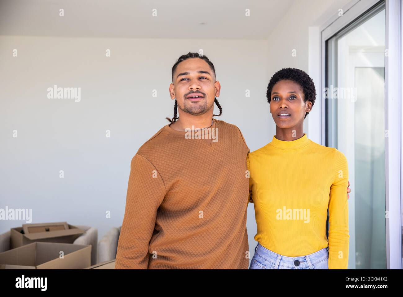 Diverse coppie in piedi all'interno di un nuovo salotto di casa con scatole mobili di cartone e porta di vetro Foto Stock