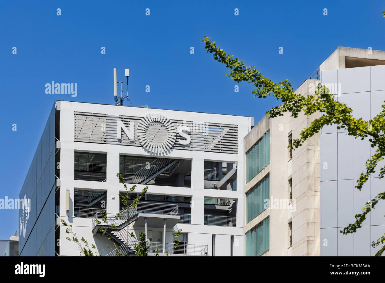 Una foto ravvicinata della facciata bianca simile a una griglia di un edificio moderno con il logo NOS, adagiata su un cielo blu brillante. Lisbona, Portogallo. Agosto 2025. Foto Stock