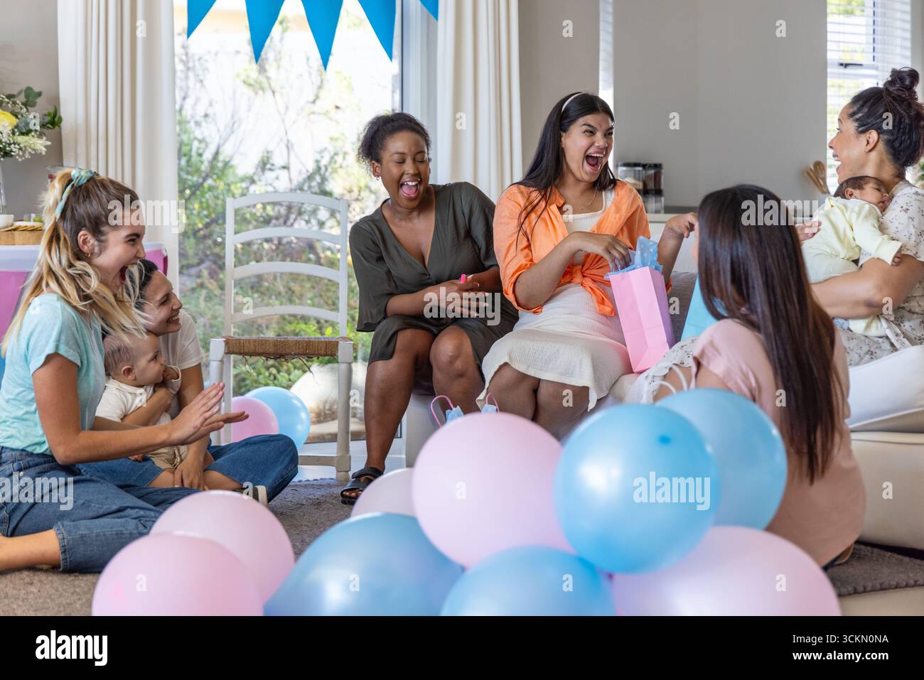 Borsa regalo per la mamma in attesa nel soggiorno circondata da palloncini color pastello Foto Stock