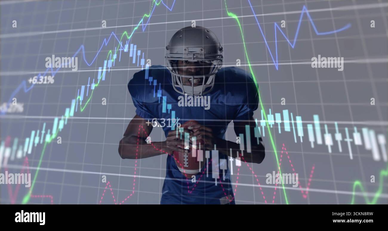 Giocatore di football americano con casco d'argento e maglia blu che tiene il football in studio, con classifiche Foto Stock