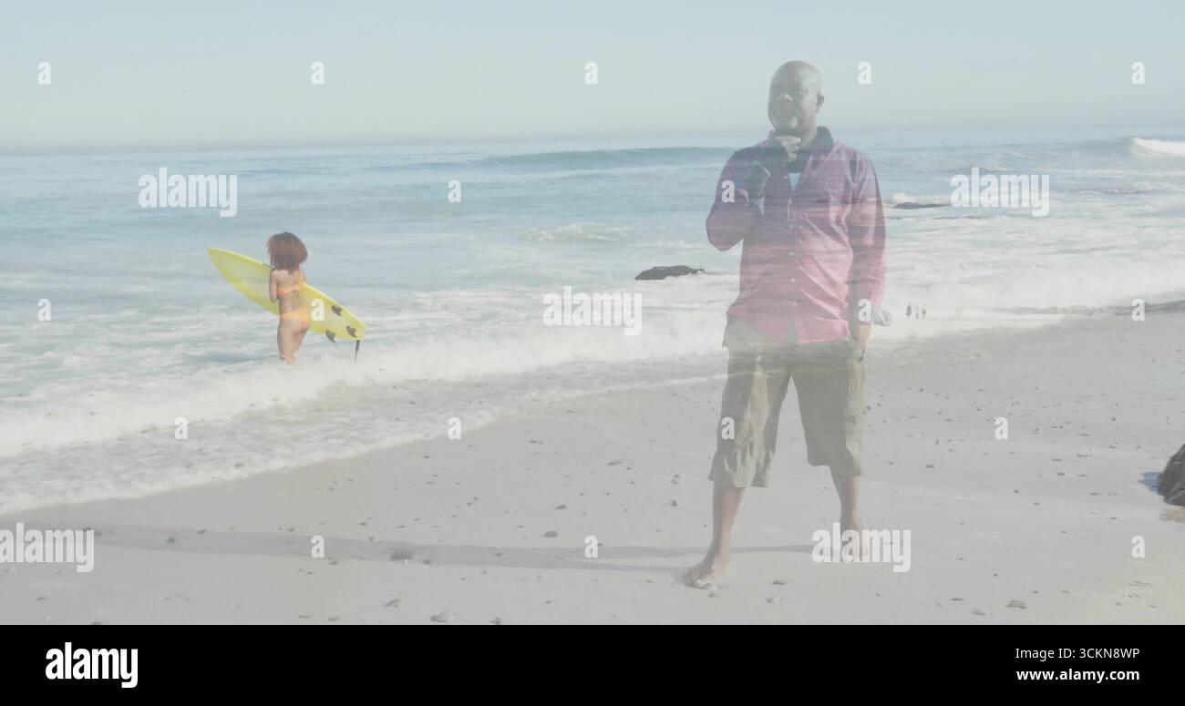 Sorseggia un uomo anziano che indossa una camicia rossa sulla costa sabbiosa, con tavola da surf gialla, spazio per copiare Foto Stock