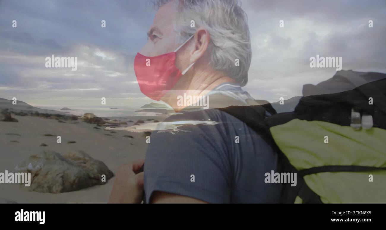 Uomo in piedi che indossa una copertura rossa sulla costa rocciosa all'alba, con zaino da trekking e spazio per copiare Foto Stock