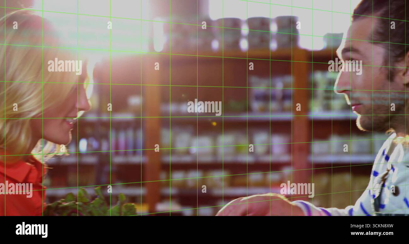 Due amici che afferrano verdi frondosi e cercano i pomodori nel corridoio della spesa, con ripiani in legno Foto Stock