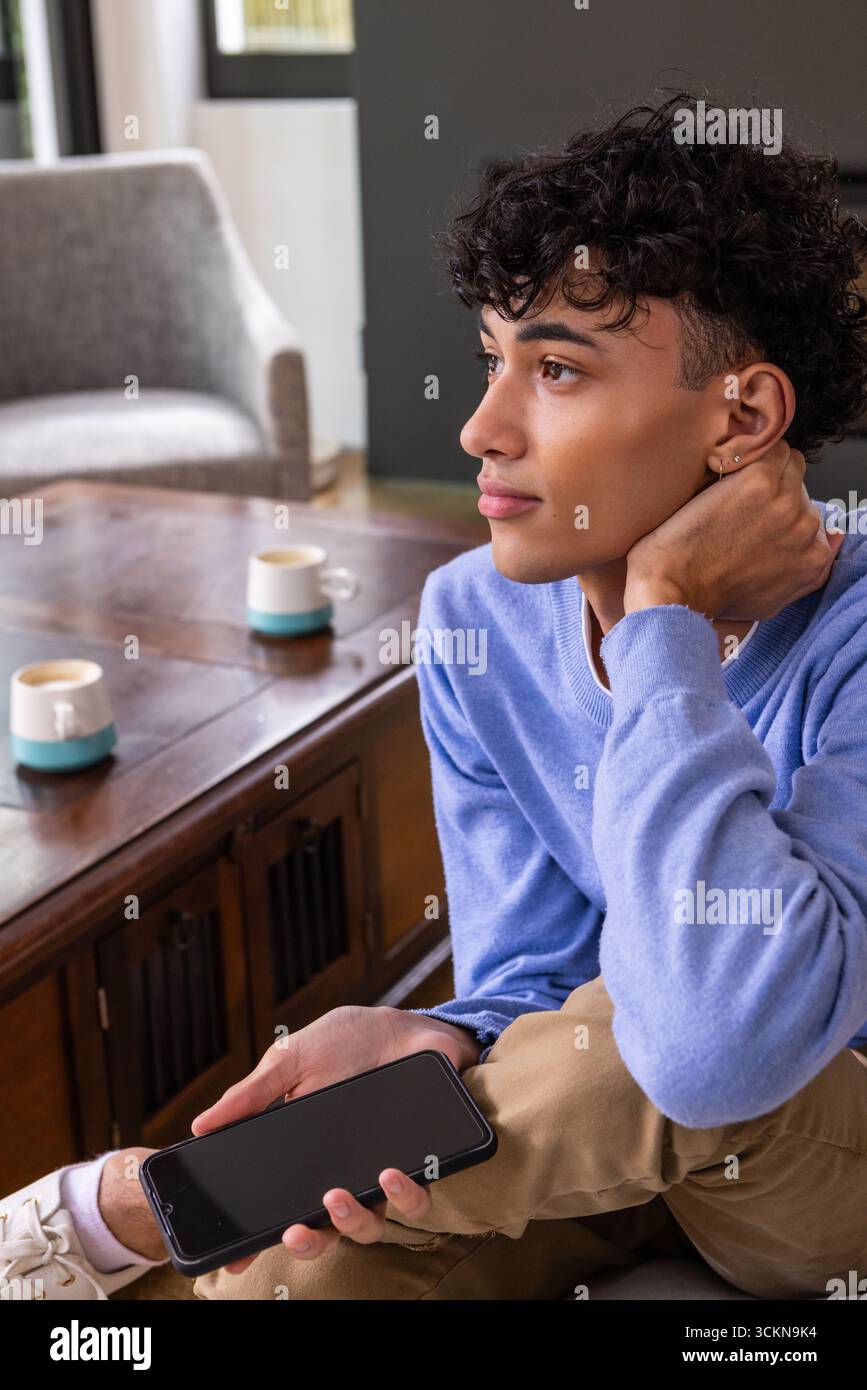 Uomo ispanico con smartphone, collo in salotto con tazze, spazio per copiare Foto Stock