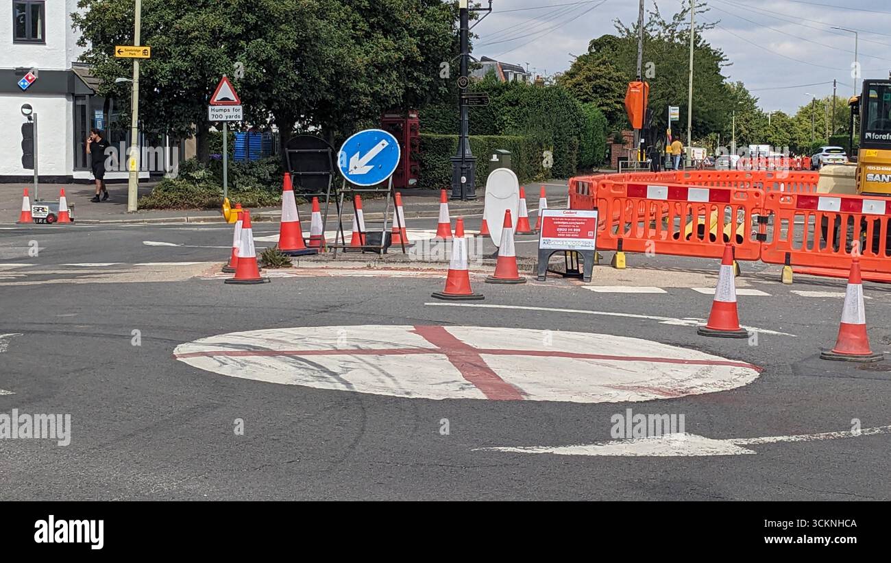 Sawbridgeworth, Inghilterra, 08/23/2025 – le rotatorie a Sawbridgeworth, Hertfordshire, sono state dipinte con la Croce di San Giorgio come parte dell'operazione Raise the Colours, una campagna che celebra l'orgoglio e l'identità nazionali. I contrassegni sono stati introdotti durante i lavori stradali in corso, con coni, barriere e segnali di deviazione in posizione per gestire il flusso del veicolo mentre le attività di costruzione e manutenzione continuano. Foto Stock