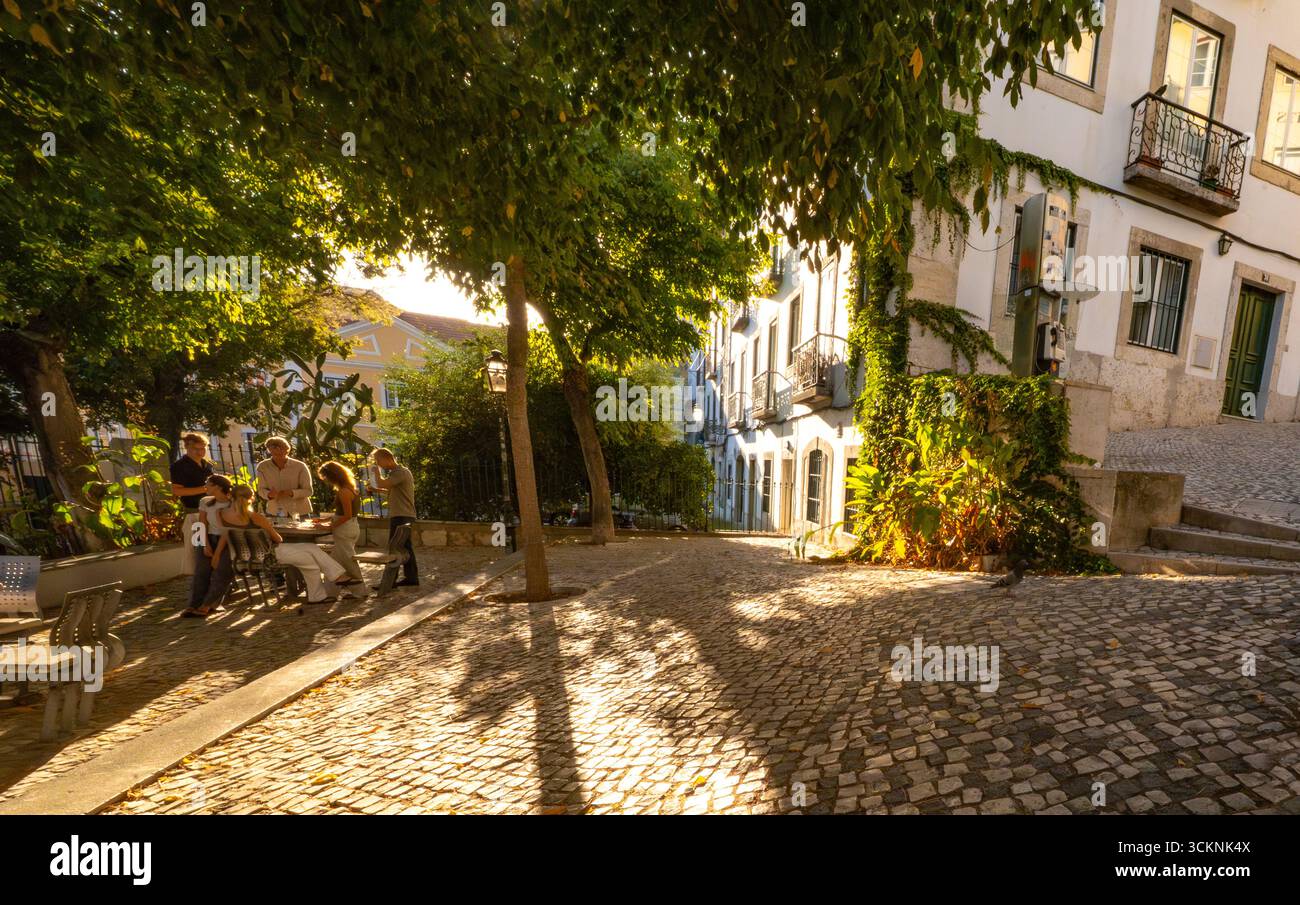 Lisbona segreta: la gente del posto si ritrova su una piazza ombreggiata dagli alberi, nel quartiere di Misericórdia, Lisbona, Portogallo, al tramonto Foto Stock