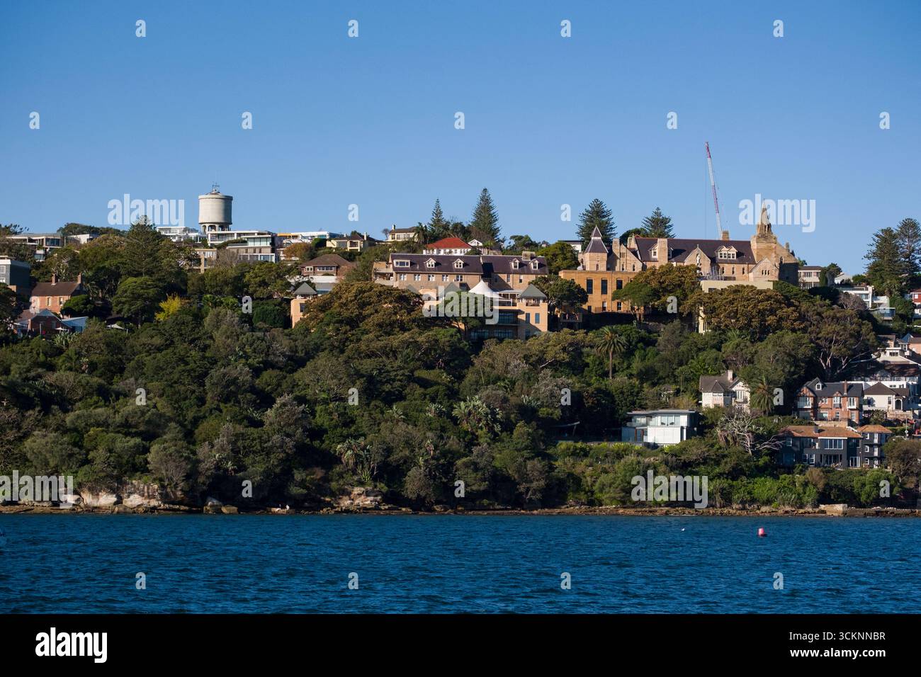 Vista luminosa e pittoresca di un tranquillo quartiere residenziale con vegetazione lussureggiante, un mix di stili architettonici e un tranquillo ambiente costiero. La sc Foto Stock