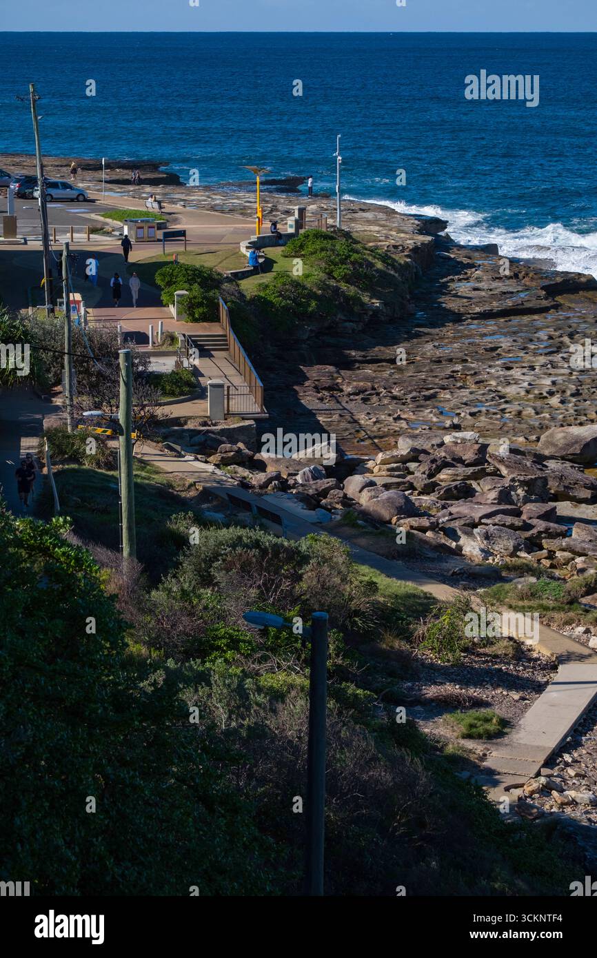 Vista panoramica sulla costa con sentiero per passeggiate, costa rocciosa, vegetazione lussureggiante e oceano blu sotto la luce del giorno. Persone che amano le attività all'aperto in Foto Stock