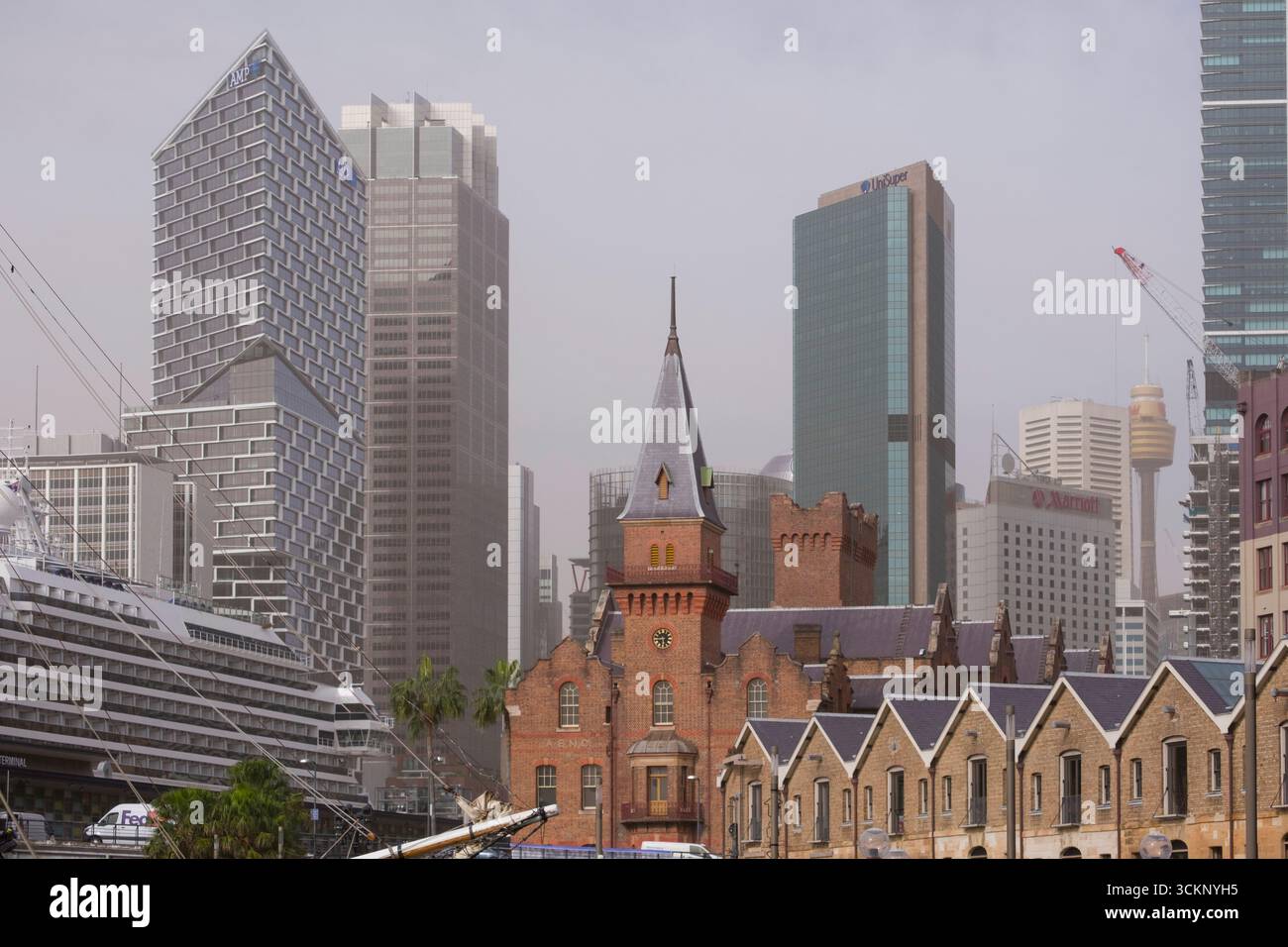 Un paesaggio urbano che mostra un mix di edifici storici in mattoni e moderni grattacieli sotto un cielo nebbioso, The Rocks, Sydney Foto Stock