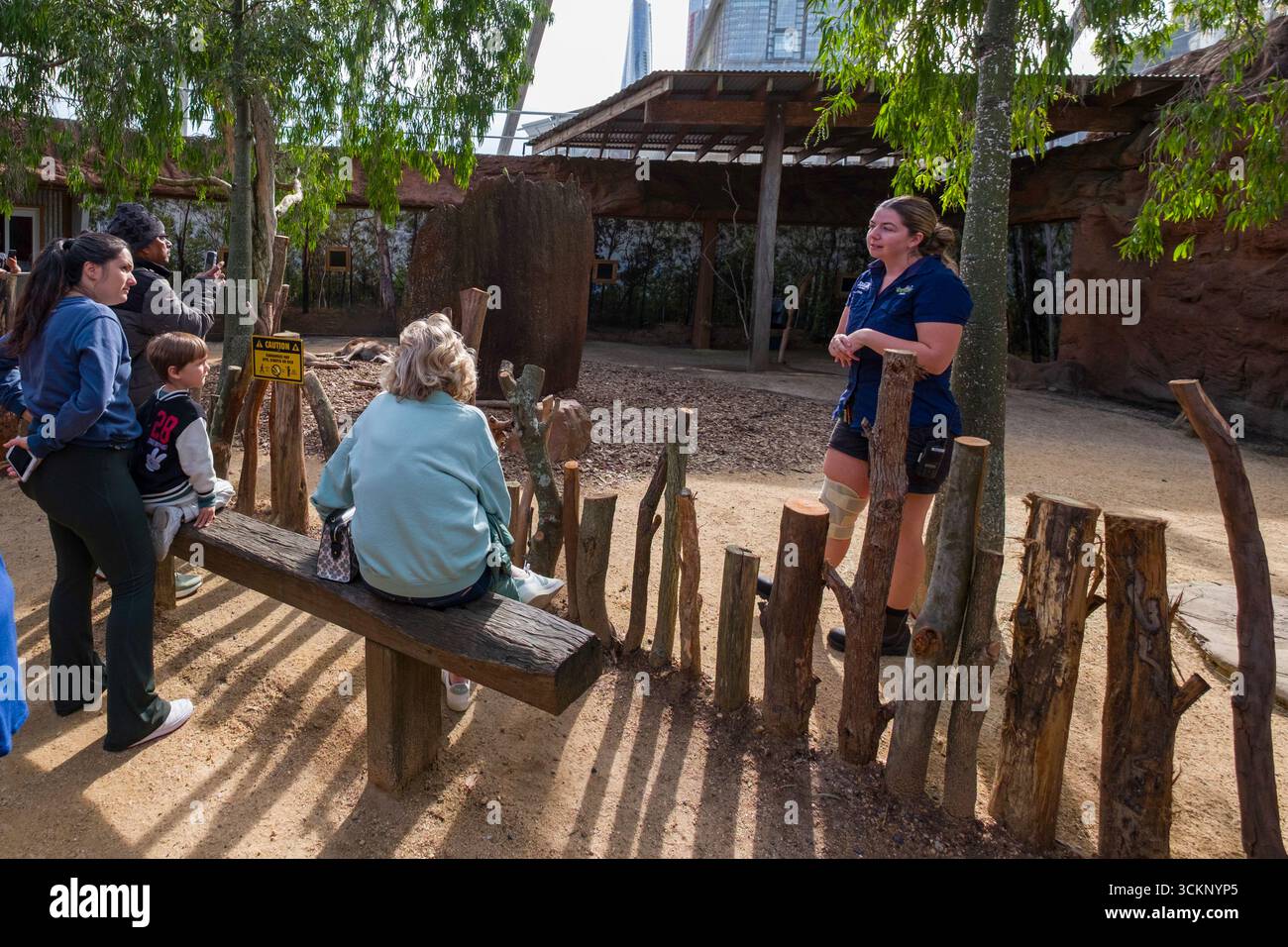 Un membro del personale WILD LIFE dello zoo di Sydney interagisce con i visitatori, condividendo informazioni sulle mostre di animali in un ambiente all'aperto, Sydney Foto Stock