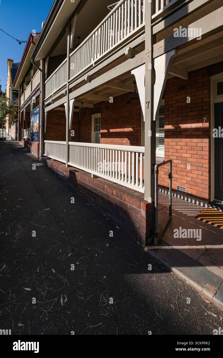 Edificio in mattoni con balcone orizzontale in legno, che offre una panoramica architettonica del design residenziale urbano in una giornata limpida, Millers Point, Sydney Foto Stock
