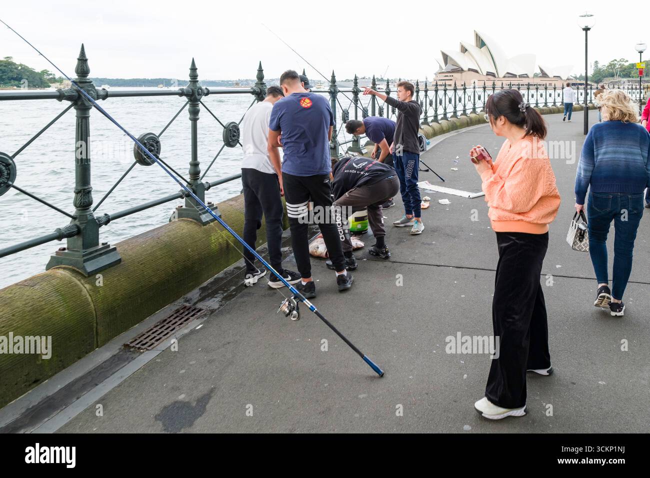 Un gruppo di persone che amano le attività di pesca ricreativa sul lungomare, sullo sfondo di un teatro dell'opera famoso in tutto il mondo, in mostra Foto Stock