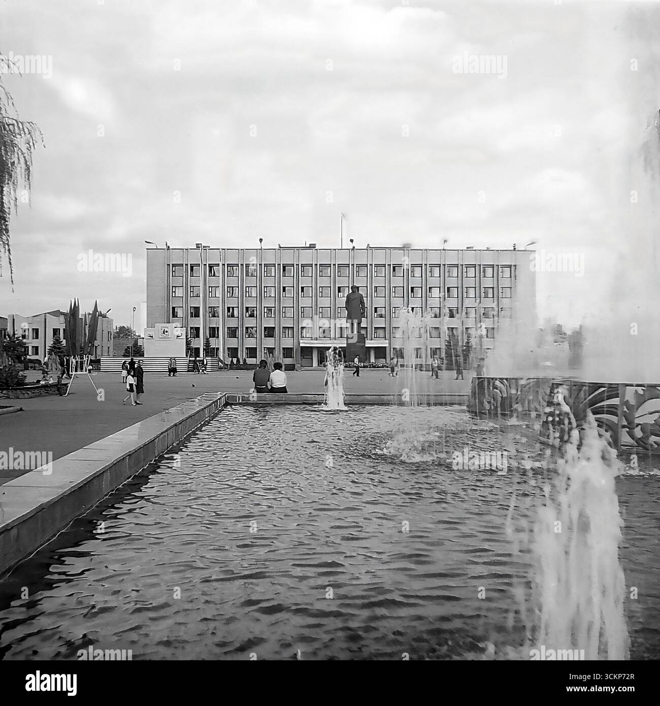 Una vista panoramica della piazza centrale della Rivoluzione d'ottobre (ora Piazza Soborna) a Sloviansk durante la celebrazione della giornata della città nel 1988. In primo piano è attiva una fontana dove i cittadini si rilassano, mentre sullo sfondo si erge un monumentale edificio amministrativo e un monumento di Lenin. Questa immagine è un simbolo della vita pacifica e prospera nel Donbas durante l'era sovietica, catturando il luogo principale per eventi pubblici e per il tempo libero molto prima dei tragici eventi del XXI secolo Foto Stock