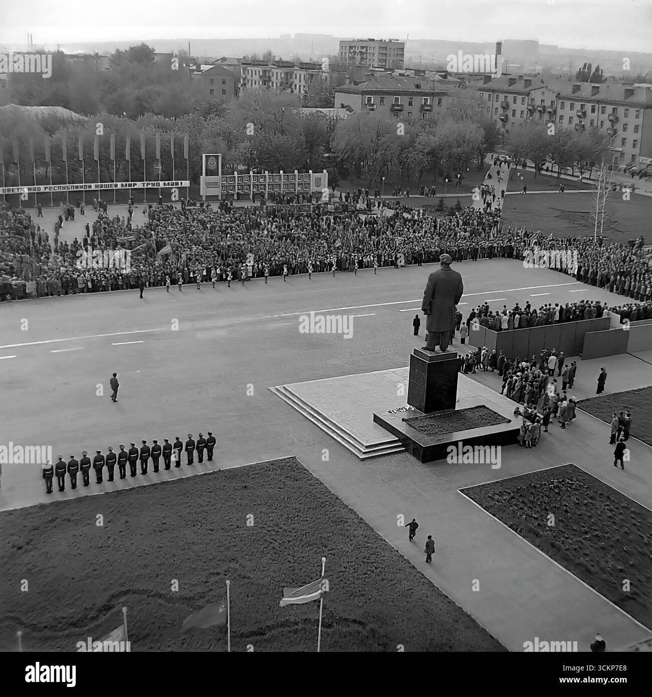 Una dimostrazione su larga scala del giorno di maggio in Piazza della Rivoluzione d'ottobre (ora Piazza Soborna) a Sloviansk, 1970 Migliaia di lavoratori con bandiere e una 'pace! Travaglio! Maggio!" Striscione marciano oltre la tribuna con la leadership e il monumento Lenin. Questo scatto è un vivido documento di un rituale di stato sovietico dell'era della stagnazione e un simbolo della vita collettiva e pacifica nel Donbas, molto prima dei tragici eventi futuri Foto Stock