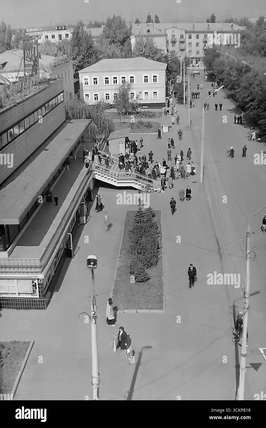 Vista panoramica del grande magazzino Yubileyniy (Jubilee) a Sloviansk, 1976. L'edificio, in stile modernista sovietico e situato in Piazza della Rivoluzione d'ottobre (ora Piazza Soborna), è mostrato come un centro del commercio urbano e della vita sociale. Gli scatti riflettono la vita quotidiana e l'architettura dell'era della stagnazione, simboleggiando la vita pacifica e ben tenuta a Donbas, dove il negozio centrale era un punto di attrazione per migliaia di cittadini Foto Stock
