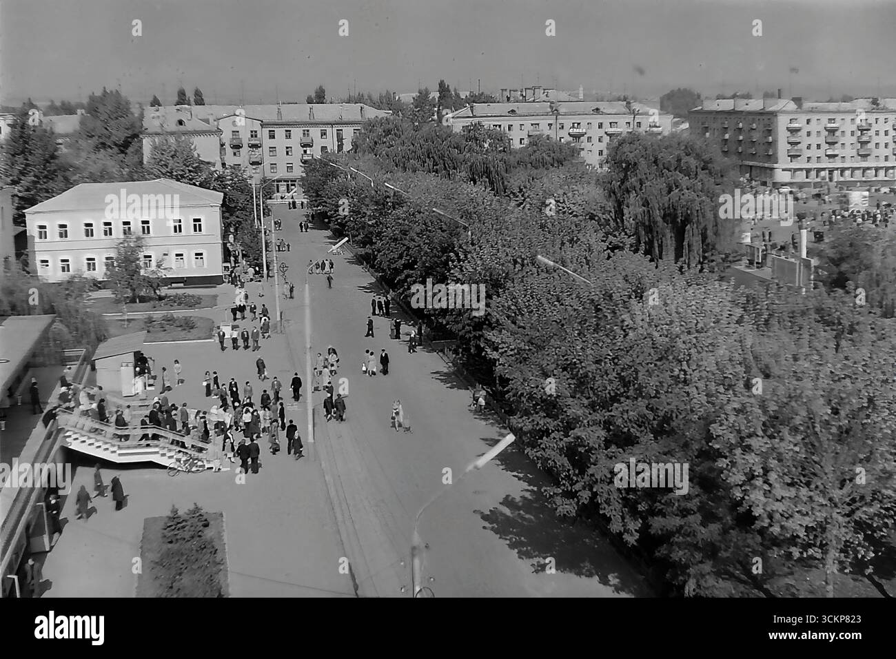 Viste estese del grande magazzino "Yubileyniy" (Jubilee) e dell'adiacente Piazza della Rivoluzione d'ottobre a Sloviansk, 1976. La serie mostra l'edificio modernista sovietico da più angolazioni e la vivace vita cittadina che ha ancorato, con folle di pedoni sui marciapiedi e sulla piazza circostanti. Questi scatti riflettono in modo vivido il ruolo centrale del grande magazzino come centro principale di commercio e attività sociale nel Donbas durante l'era della stagnazione, preservando il ricordo di una comunità vivace e pacifica Foto Stock