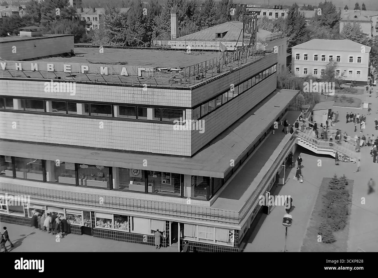 Vista panoramica del grande magazzino Yubileyniy (Jubilee) a Sloviansk, 1976. L'edificio, in stile modernista sovietico e situato in Piazza della Rivoluzione d'ottobre (ora Piazza Soborna), è mostrato come un centro del commercio urbano e della vita sociale. Gli scatti riflettono la vita quotidiana e l'architettura dell'era della stagnazione, simboleggiando la vita pacifica e ben tenuta a Donbas, dove il negozio centrale era un punto di attrazione per migliaia di cittadini Foto Stock