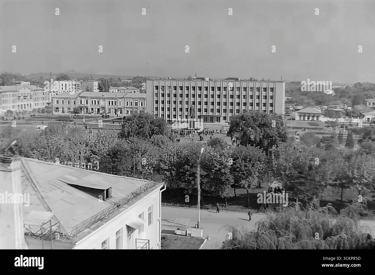 Viste panoramiche della piazza centrale della Rivoluzione d'ottobre (ora piazza Soborna) a Sloviansk, 1976, durante una grande festa pubblica. Migliaia di cittadini sono visti rilassarsi e passeggiare attraverso la piazza verdeggiante sullo sfondo di edifici amministrativi e residenziali. Questi scatti sono un potente simbolo della vita sociale pacifica, ordinata e vibrante nel Donbas durante l'era della stagnazione, catturando lo spirito della comunità della città molto prima dei tragici eventi che hanno distrutto questa esistenza idilliaca Foto Stock