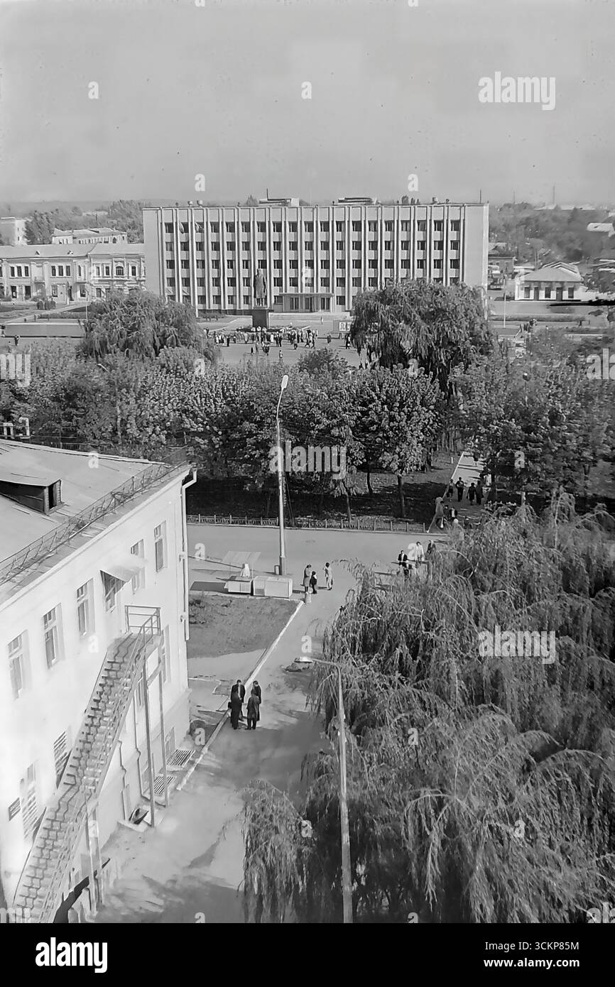 Viste panoramiche della piazza centrale della Rivoluzione d'ottobre (ora piazza Soborna) a Sloviansk, 1976, durante una grande festa pubblica. Migliaia di cittadini sono visti rilassarsi e passeggiare attraverso la piazza verdeggiante sullo sfondo di edifici amministrativi e residenziali. Questi scatti sono un potente simbolo della vita sociale pacifica, ordinata e vibrante nel Donbas durante l'era della stagnazione, catturando lo spirito della comunità della città molto prima dei tragici eventi che hanno distrutto questa esistenza idilliaca Foto Stock