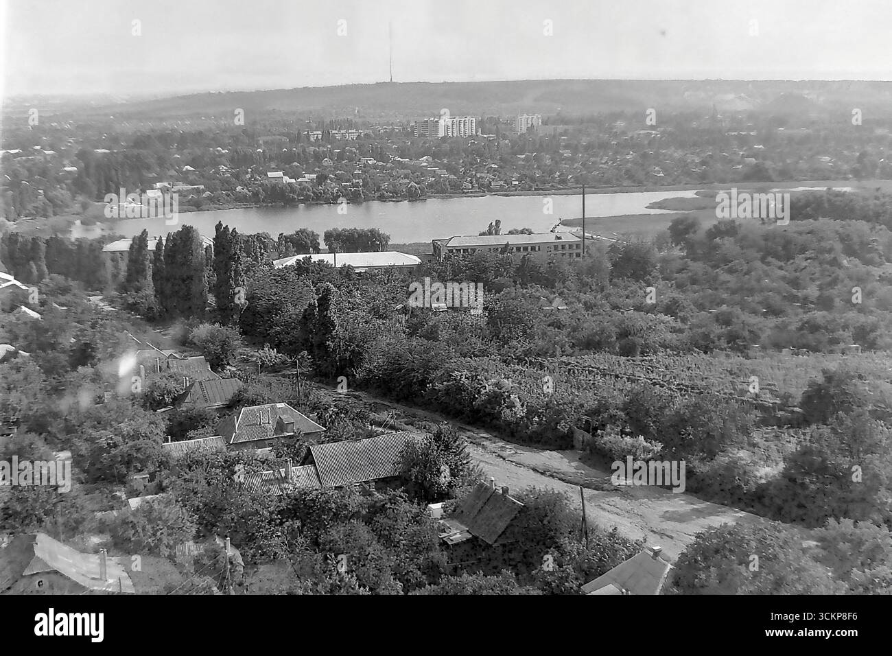 Un'ampia vista panoramica di Slovyansk, RSS Ucraina, dal distretto elevato di Artyoma negli anni '1980 Il vasto paesaggio cattura la geografia unica della città, mostrando i vasti "vigneti" in primo piano, il campus della scuola professionale n. 57 sulla riva di un grande lago e le principali zone urbane e industriali che si estendono fino all'orizzonte. Questa immagine mozzafiato simboleggia l'armoniosa miscela di natura e vita cittadina nel tranquillo Donbas, mostrando una comunità pittoresca e fiorente durante l'ultimo decennio dell'URSS Foto Stock