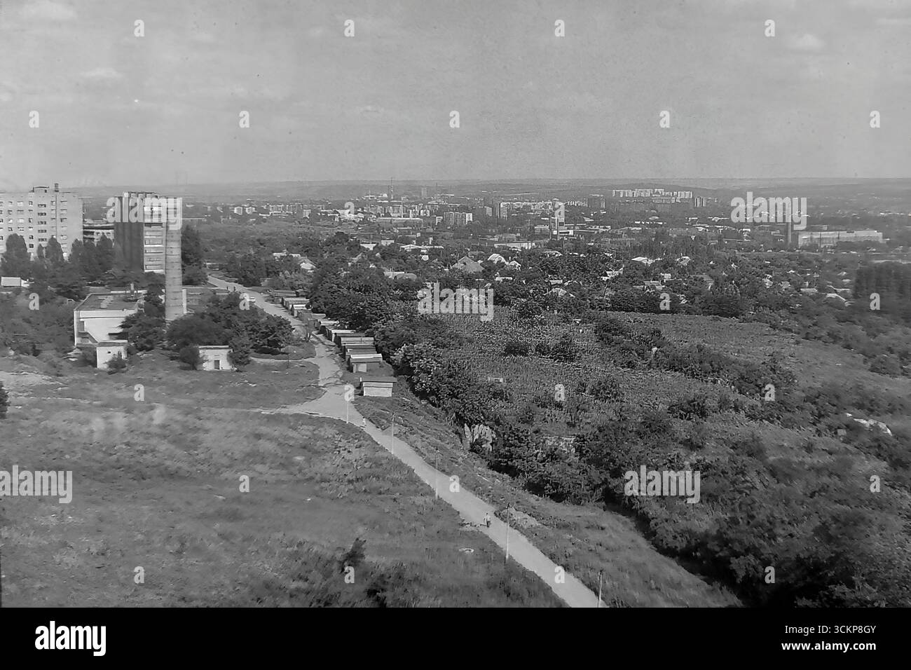 Una vista panoramica mozzafiato di Slovyansk, RSS Ucraina, dall'area sopraelevata di Lesnoy all'interno del quartiere di Artyoma durante gli anni '1980 L'ampio paesaggio, girato da un'alta collina, cattura aree residenziali, file di garage e il vasto paesaggio urbano che si estende fino all'orizzonte. Questa immagine è un potente simbolo della vita pacifica e su larga scala nel Donbas, che mostra la miscela unica e armoniosa della città con il suo terreno naturale durante l'ultimo decennio dell'URSS Foto Stock