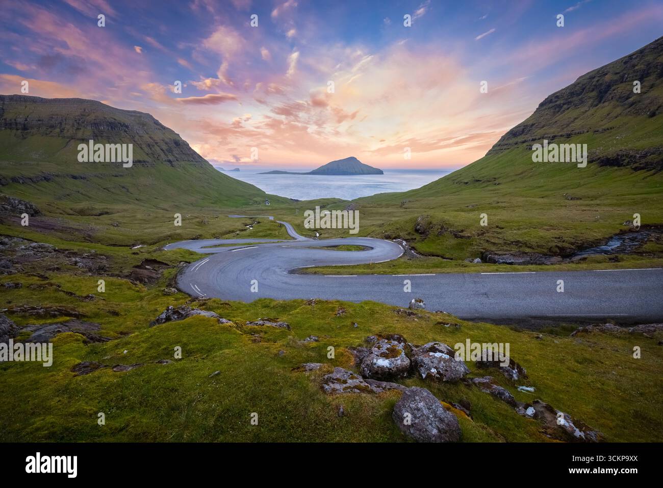 Vista su una strada tortuosa che porta all'isola di Koltur sullo sfondo. Streymoy, distretto di Torshavnar, Isole Faroe, Danimarca, Scandinavia. Foto Stock