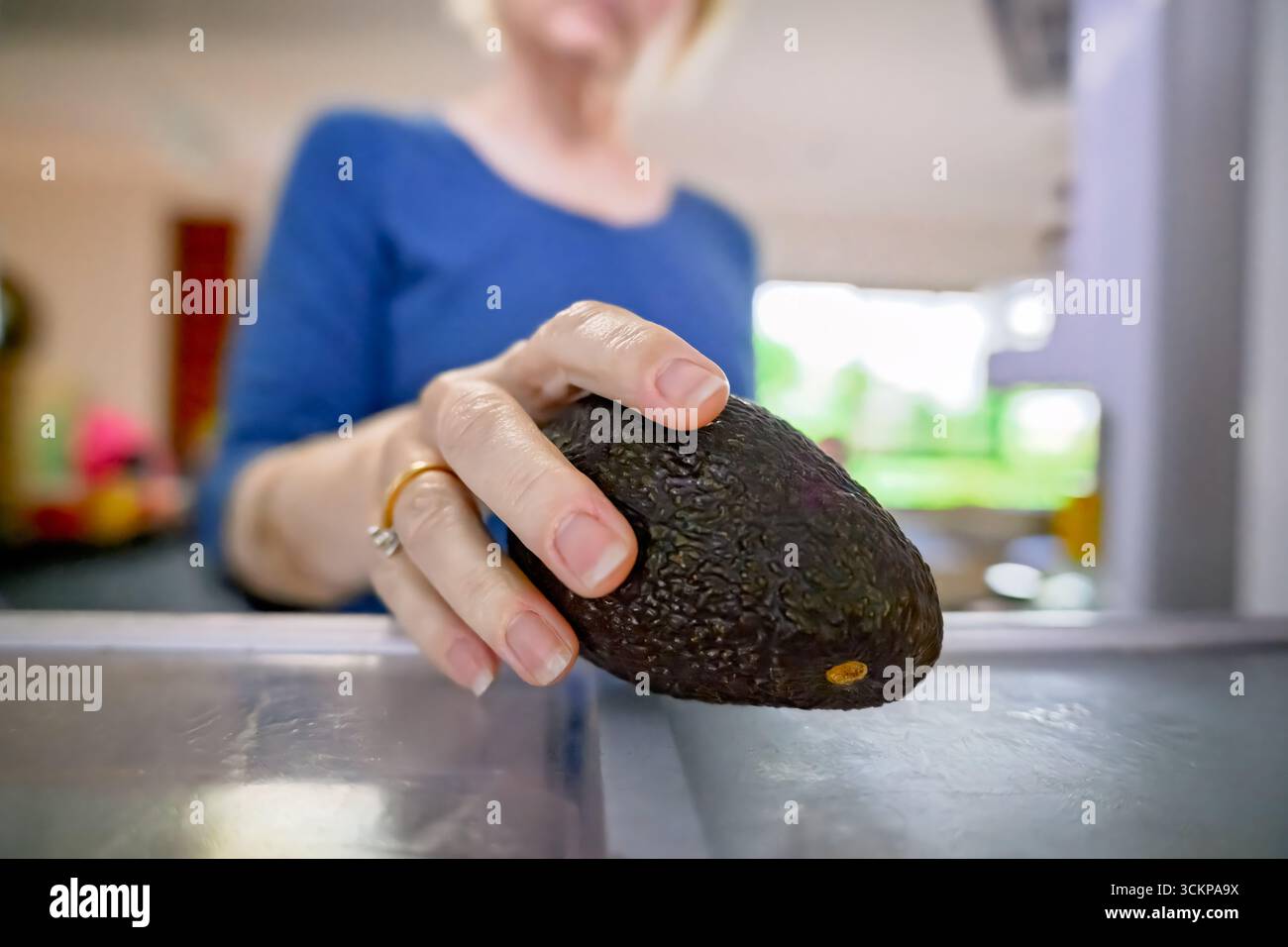 donna che porta avocado fresco fuori dal frigorifero, dal frigorifero interno, cucina la spesa quotidiana in casa Foto Stock