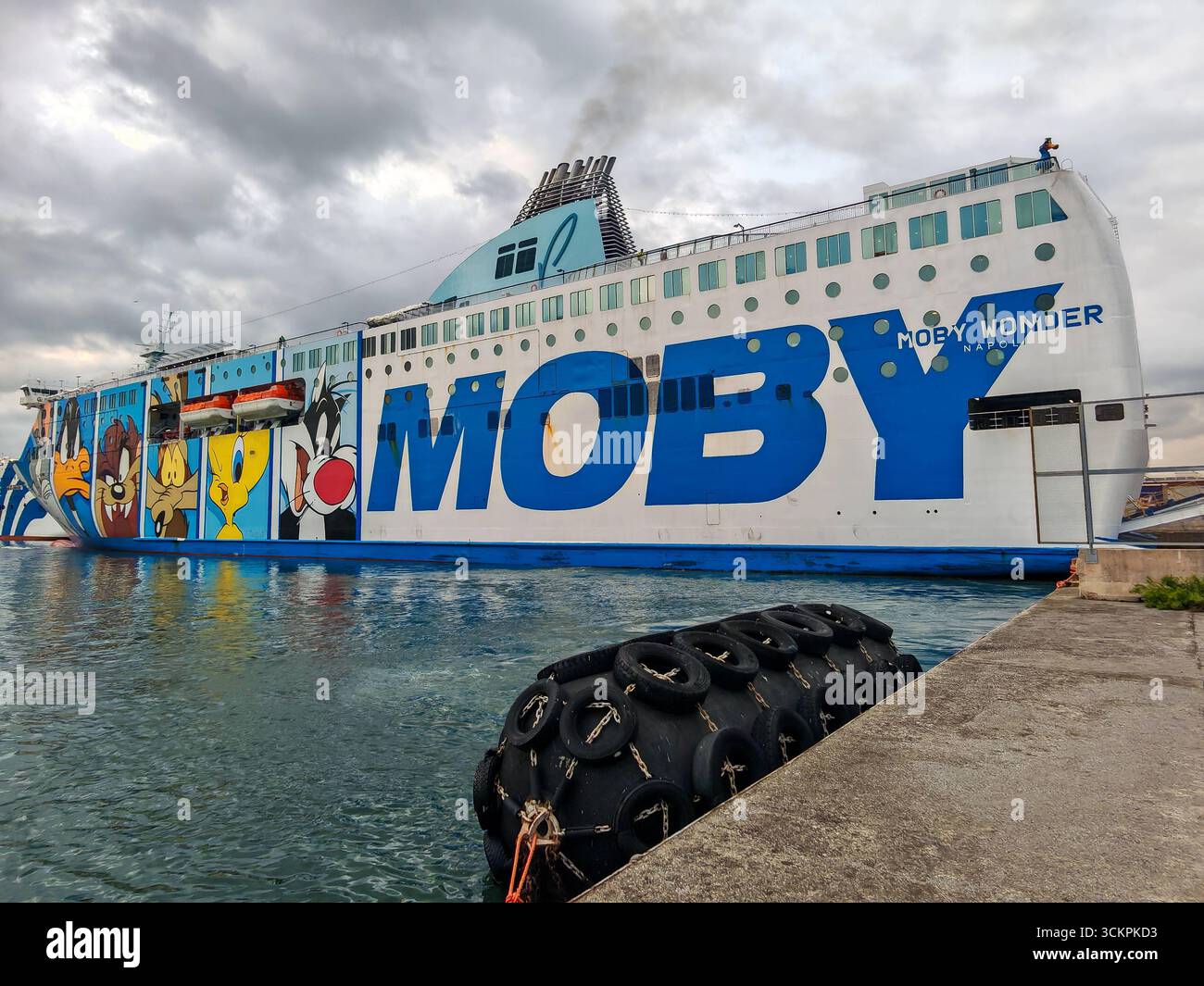 Genova, Italia - 13 settembre 2025: Il traghetto Moby Wonder è ormeggiato nel porto di Genova. La nave passeggeri e RoRo della compagnia di navigazione Moby si distingue per i suoi colorati dipinti a fumetti e collega le città portuali italiane nel Mediterraneo *** Die Autofähre Moby Wonder liegt im Hafen von Genua. DAS Passagier- und RoRo-Schiff der Reederei Moby fällt durch bunte Cartoon-Bemalungen auf und verbindet italienische Hafenstädte im Mittelmeer Foto Stock