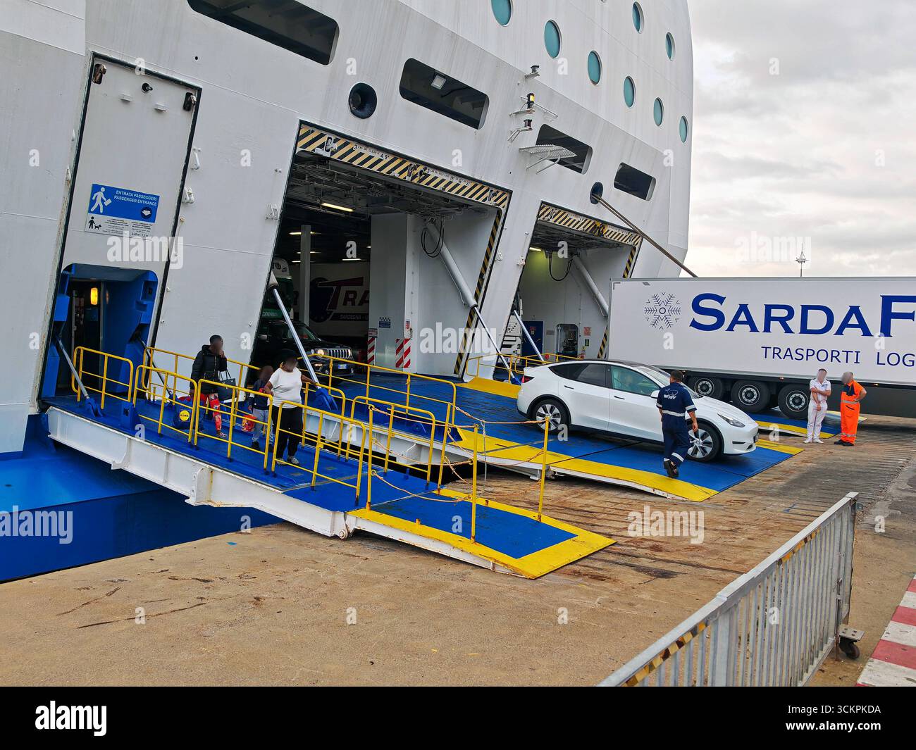 Genova, Italia - 13 settembre 2025: Una Tesla Model Y lascia il traghetto Moby Wonder nel porto di Genova. Il traghetto RoRo operato dalla compagnia di navigazione Moby trasporta passeggeri e veicoli, comprese le auto elettriche, sulle rotte mediterranee *** Ein Tesla Model Y verlässt im Hafen von Genua die Autofähre Moby Wonder. Die RoRo-Fähre der Reederei Moby transportiert Passagiere und Fahrzeuge, darunter auch Elektroautos, auf Mittelmeer-Routen Foto Stock