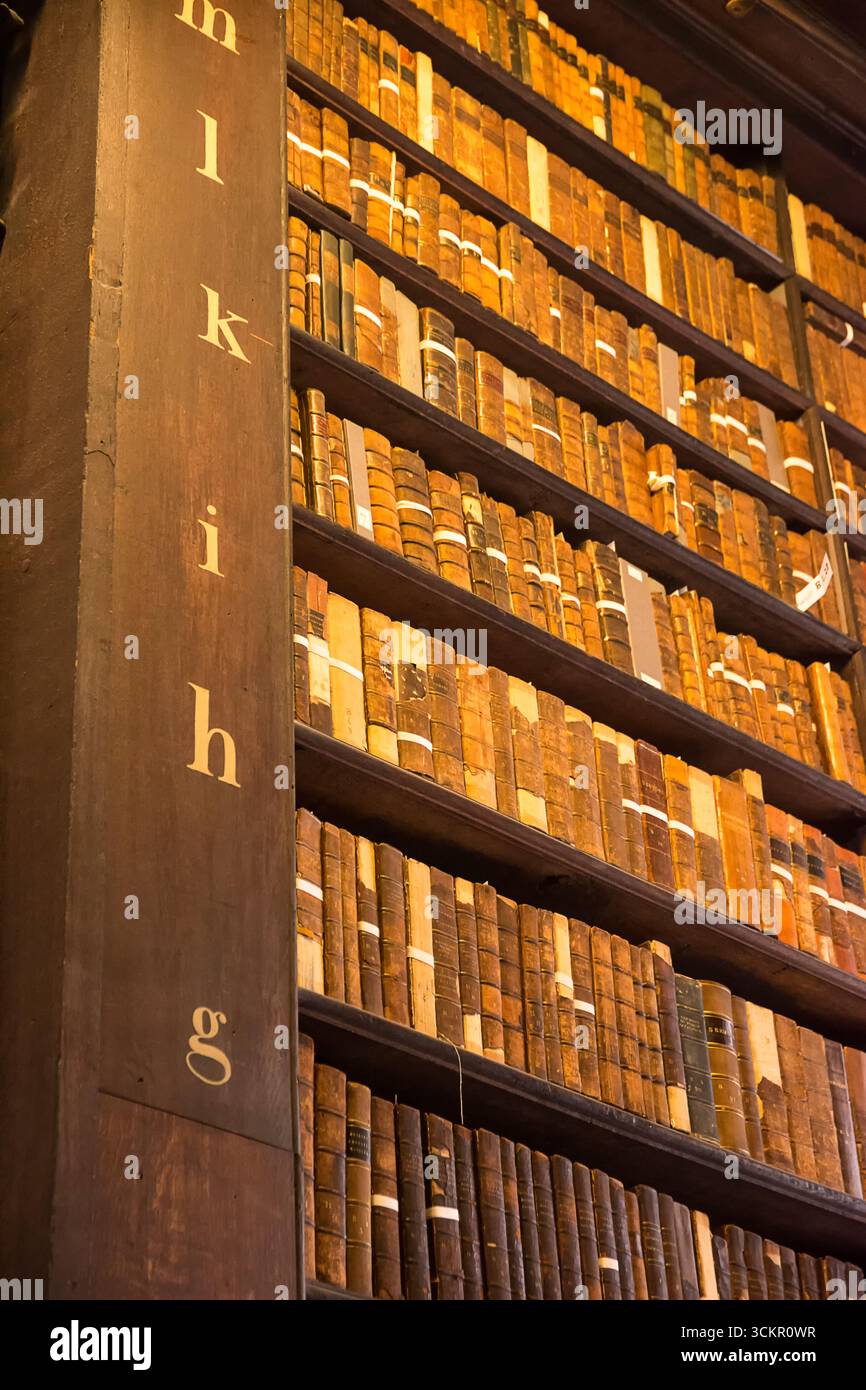 Dublino, Irlanda - 4 aprile 2025: File di libri antichi su scaffali in legno all'interno della Trinity College Library, Dublino Foto Stock