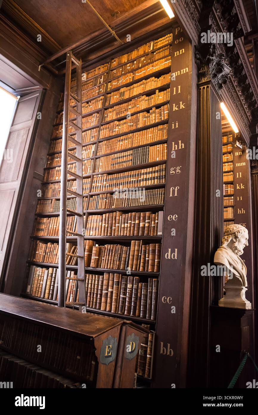 Dublino, Irlanda - 4 aprile 2025: File di libri antichi su scaffali in legno all'interno della Trinity College Library, Dublino Foto Stock