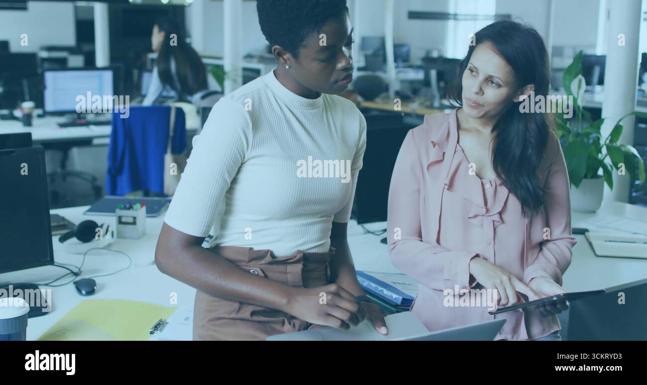 Collaborare con le donne in abiti da lavoro per discutere il progetto alla scrivania dell'ufficio, con notebook e tablet Foto Stock