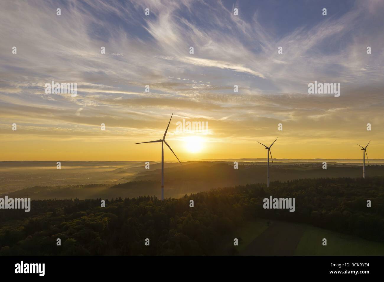 Le turbine eoliche si fermano sotto una luce solare soffusa che illumina il cielo e la foresta, nei pressi di Schorndorf, Remstal, Rems-Murr-Kreis, Baden-Wuerttemberg, tedesco Foto Stock