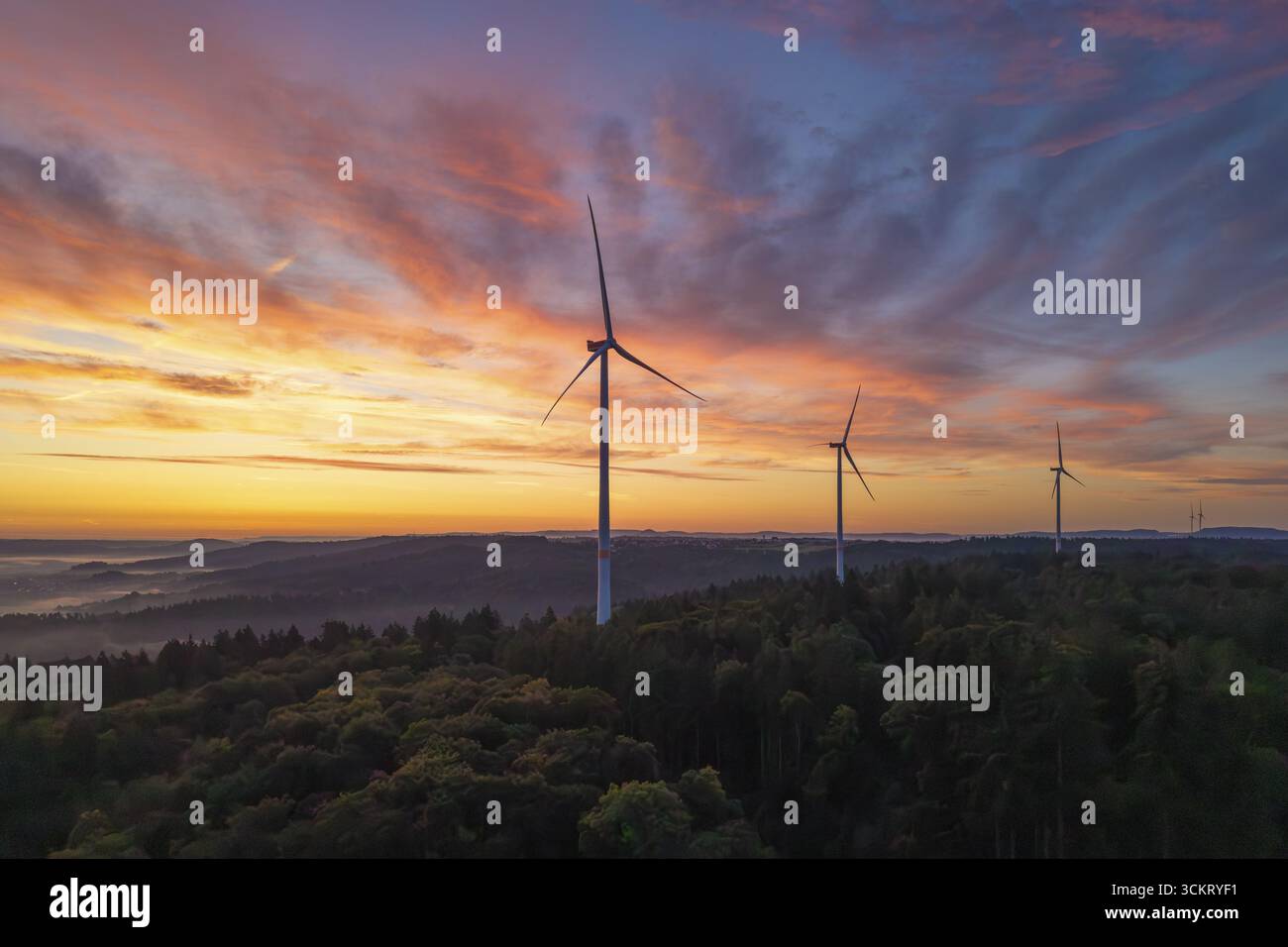 Tre turbine eoliche in primo piano in un colorato cielo mattutino su un paesaggio collinare, vicino a Schorndorf, Remstal, Rems-Murr-Kreis, Baden-Wuerttemberg Foto Stock