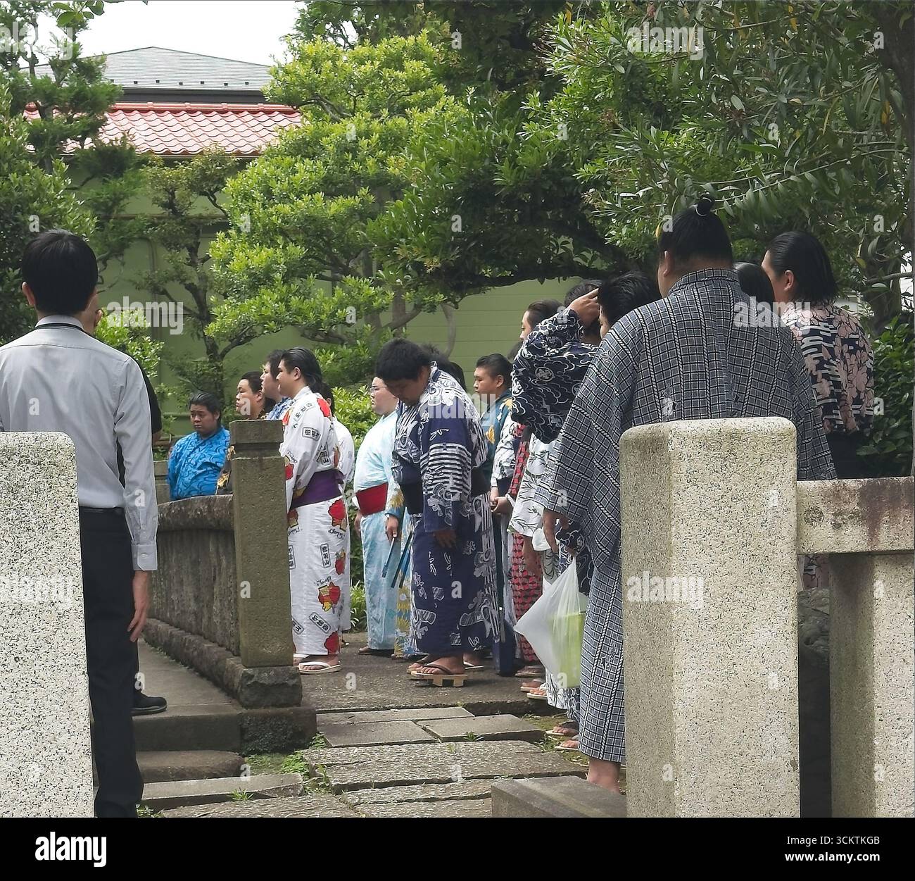 Un gruppo di individui che indossano abiti tradizionali si trova all'aperto in un ambiente sereno e culturalmente ricco. Foto Stock