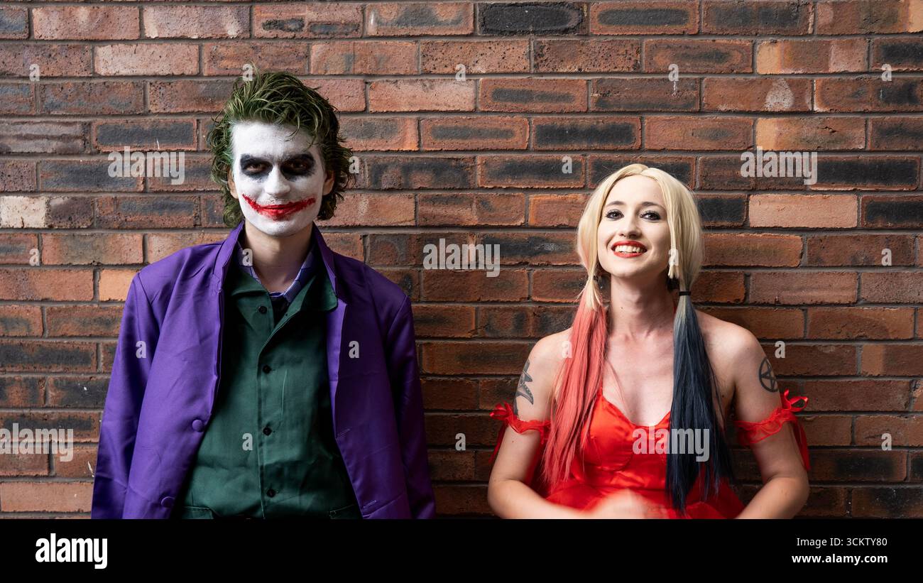 Una bella ragazza e un bel cosplayer maschio che si diverte e ride mentre si vestono da Joker e Harley Quinn con spazio per copiare sopra Foto Stock