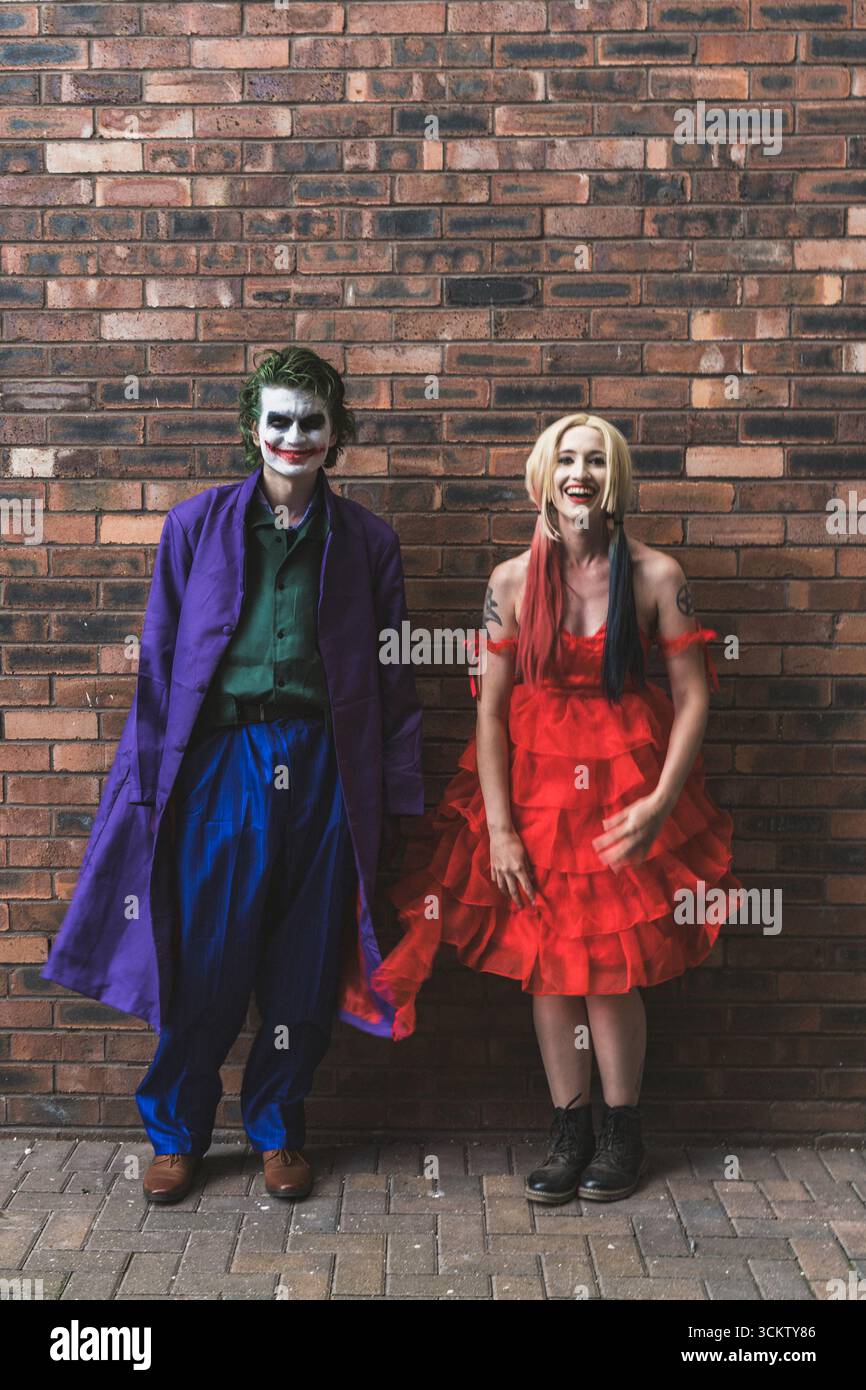 Una bella ragazza e un bel cosplayer maschio che si diverte e ride mentre si vestono da Joker e Harley Quinn con spazio per copiare sopra Foto Stock